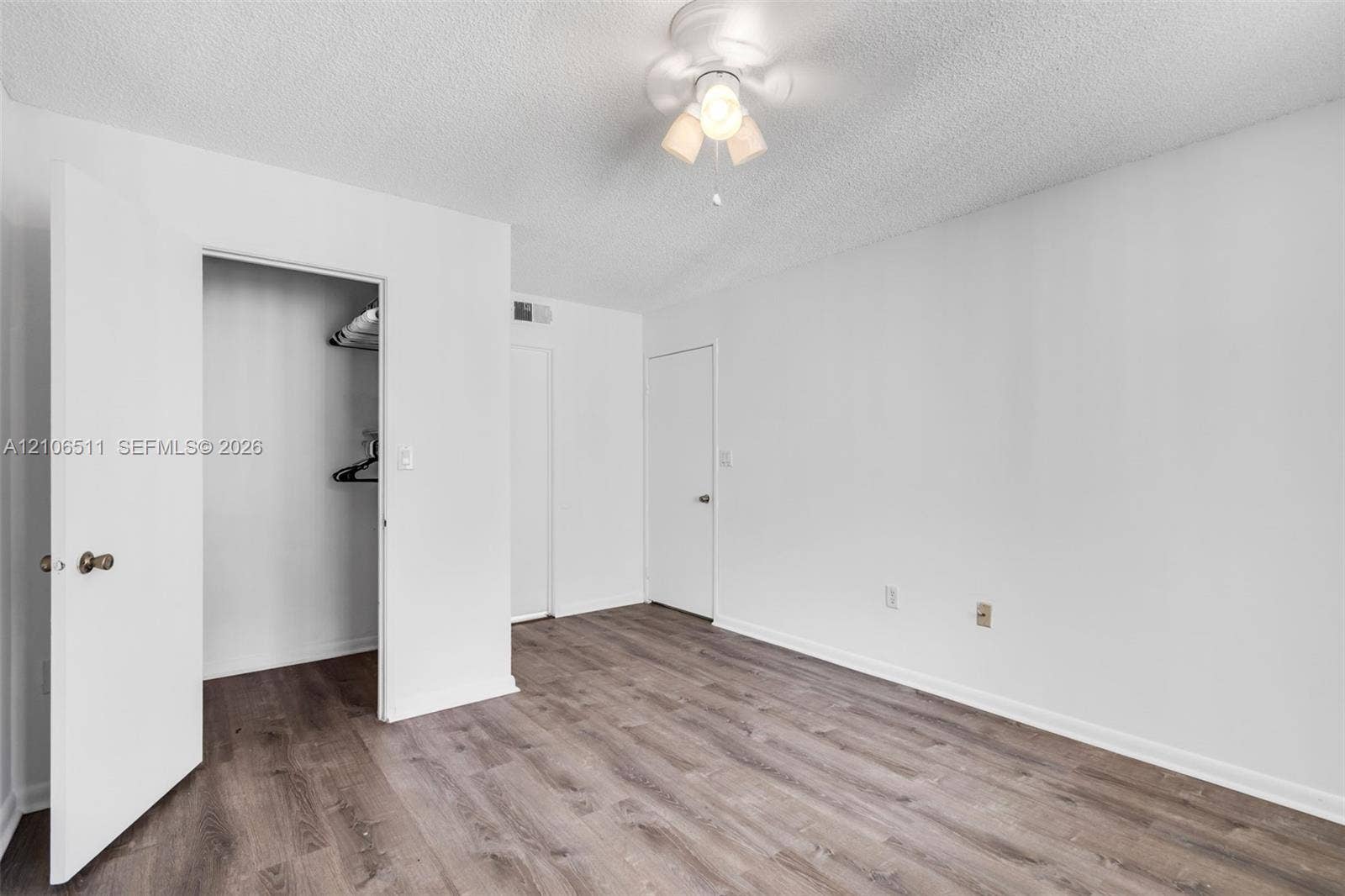 3229 Coral Lake Drive, #3229, Coral Springs, FL 33065 Interior space featuring wood-finish flooring, a built-in closet with shelving, and a flush-mount multi-bulb lighting fixture