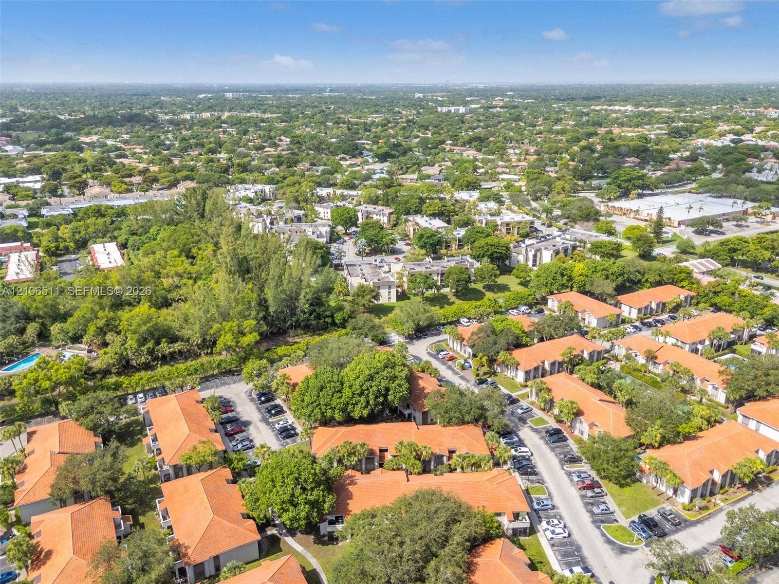 3229 Coral Lake Drive, #3229, Coral Springs, FL 33065 Aerial perspective of a multi-building residential complex featuring terra cotta-style tile roofing, mature landscaping, paved surface parking, and shared outdoor pool area