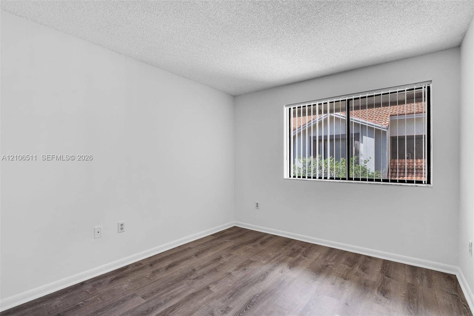 3229 Coral Lake Drive, #3229, Coral Springs, FL 33065 Interior room featuring wood-finish flooring, white walls, textured ceiling, and a window with installed vertical blinds