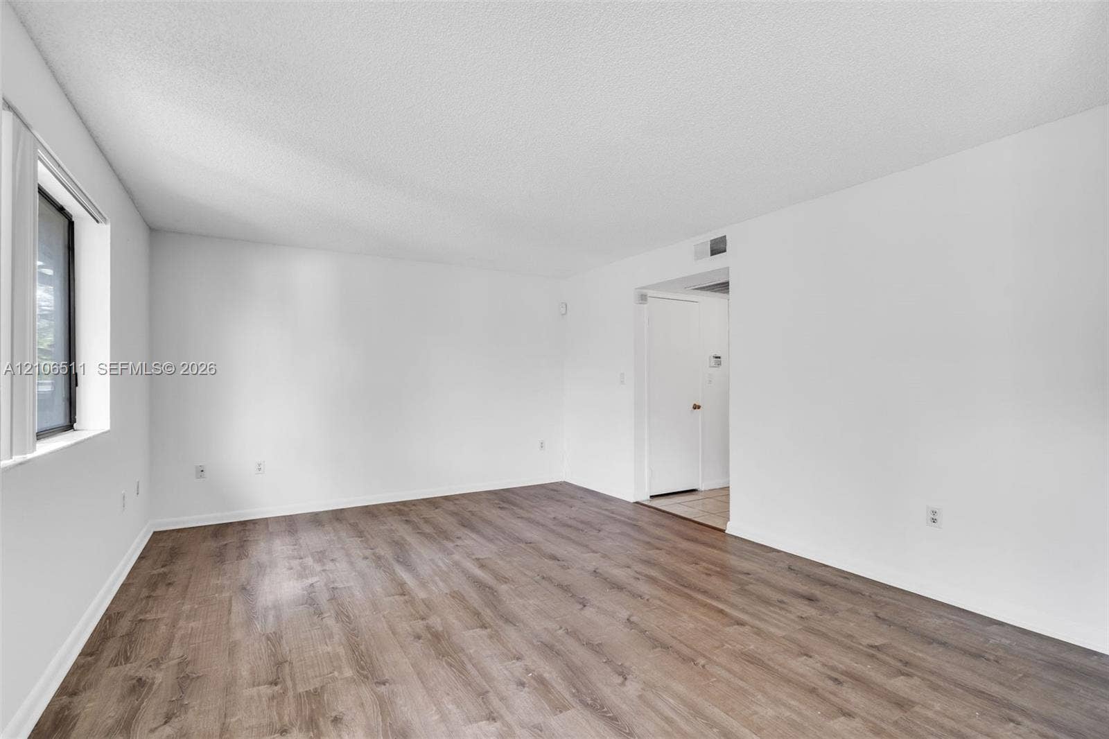 3229 Coral Lake Drive, #3229, Coral Springs, FL 33065 Neutral-toned interior space featuring wood-finish flooring, white walls, and a recessed window