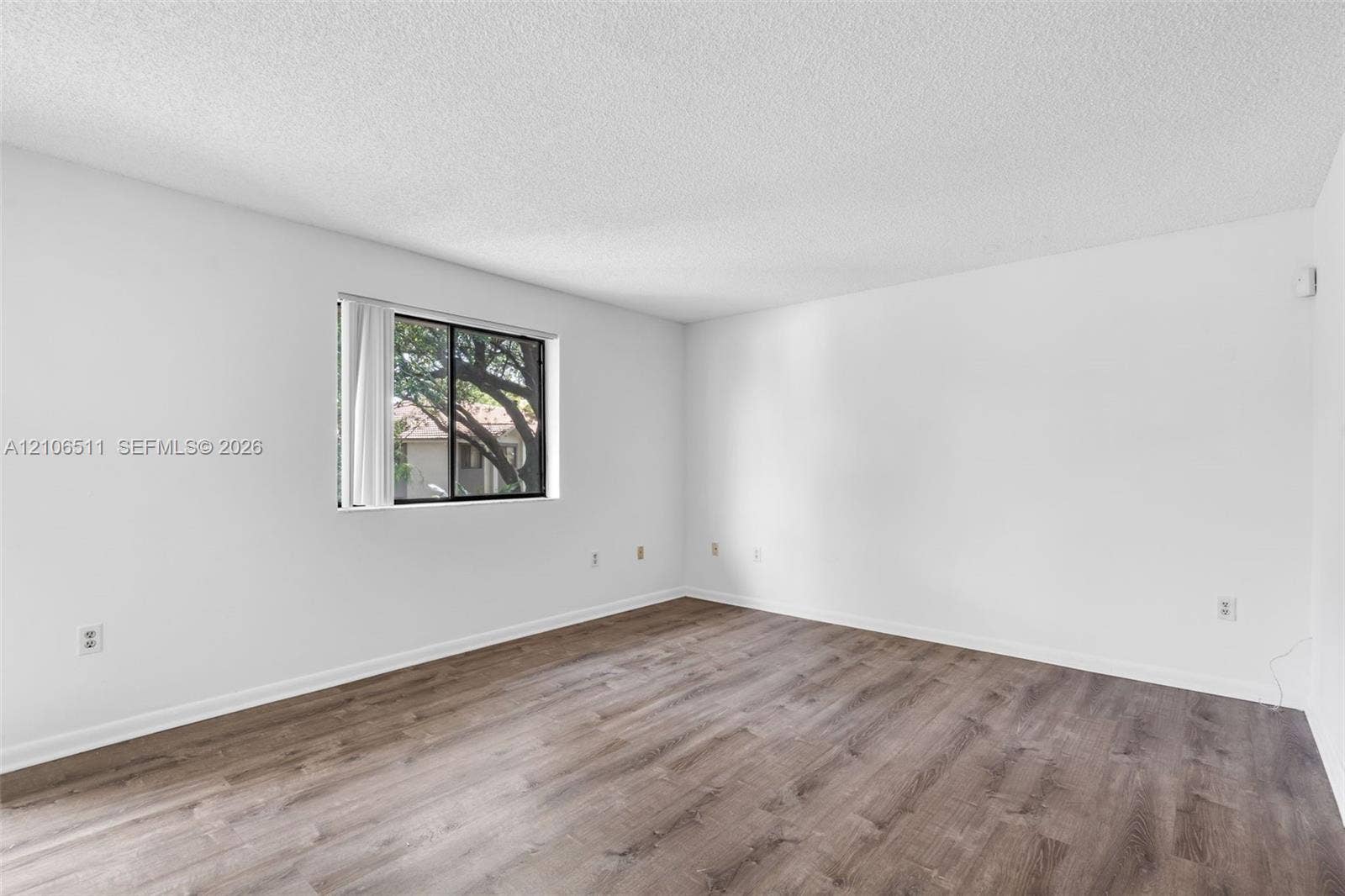 3229 Coral Lake Drive, #3229, Coral Springs, FL 33065 Interior space featuring wood-finish flooring, white walls, a single-pane window, and a textured ceiling