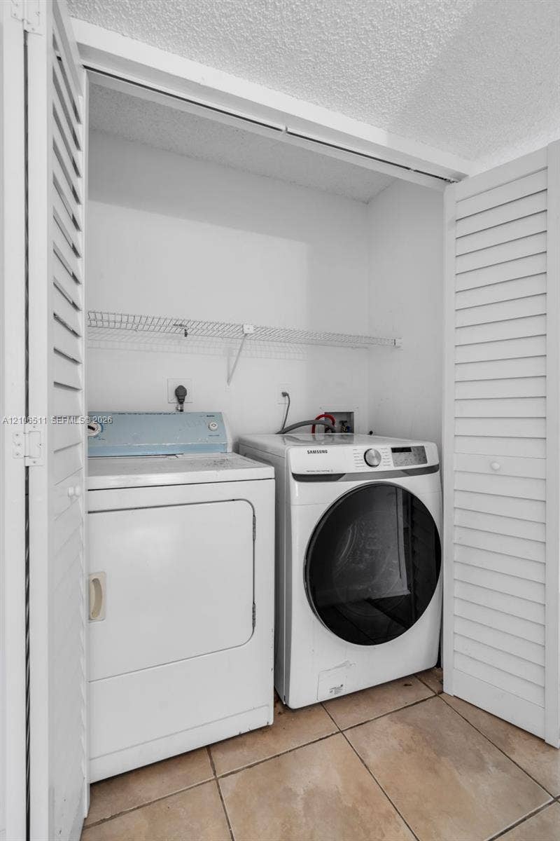 3229 Coral Lake Drive, #3229, Coral Springs, FL 33065 Laundry closet featuring white louvered doors, tile flooring, and built-in wire shelving