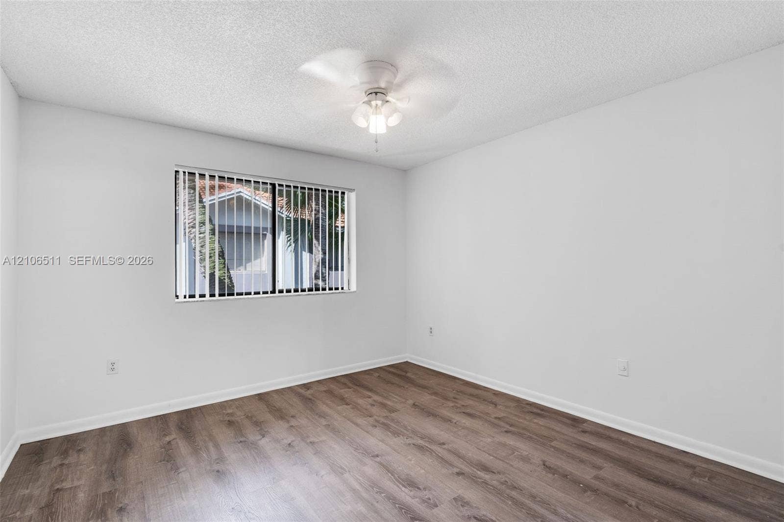 3229 Coral Lake Drive, #3229, Coral Springs, FL 33065 Room interior featuring wood-finish flooring, white walls, and a ceiling-mounted light fixture with a fan