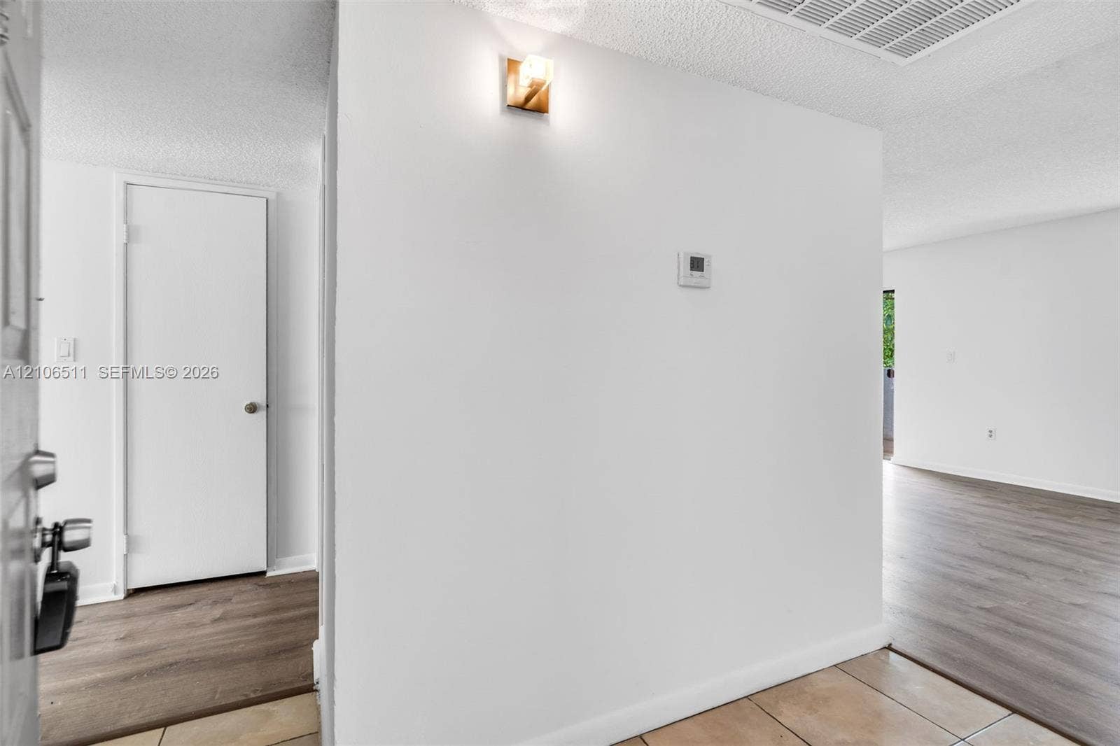 3229 Coral Lake Drive, #3229, Coral Springs, FL 33065 Interior entry featuring ceramic tile flooring, wood-finish flooring, a wall-mounted light fixture, and a solid-core interior door