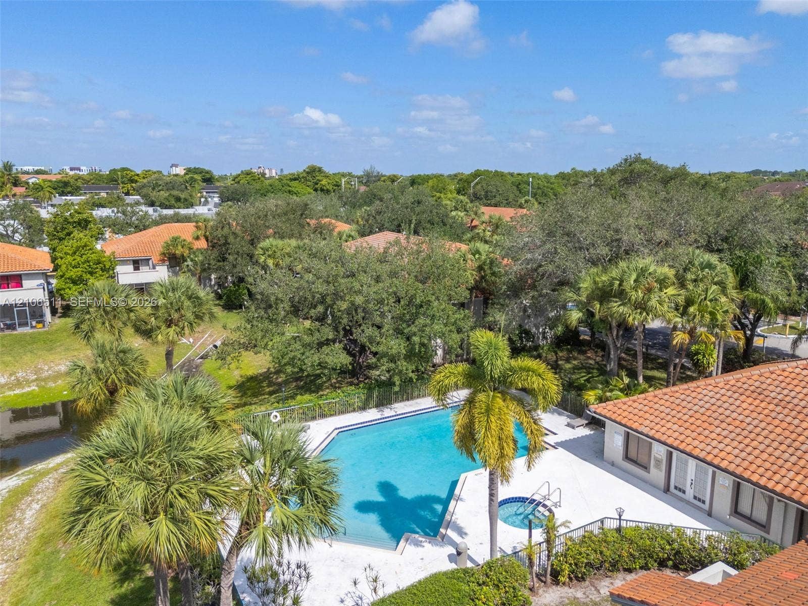 3229 Coral Lake Drive, #3229, Coral Springs, FL 33065 Outdoor swimming pool with integrated spa, concrete decking, and mature palm trees