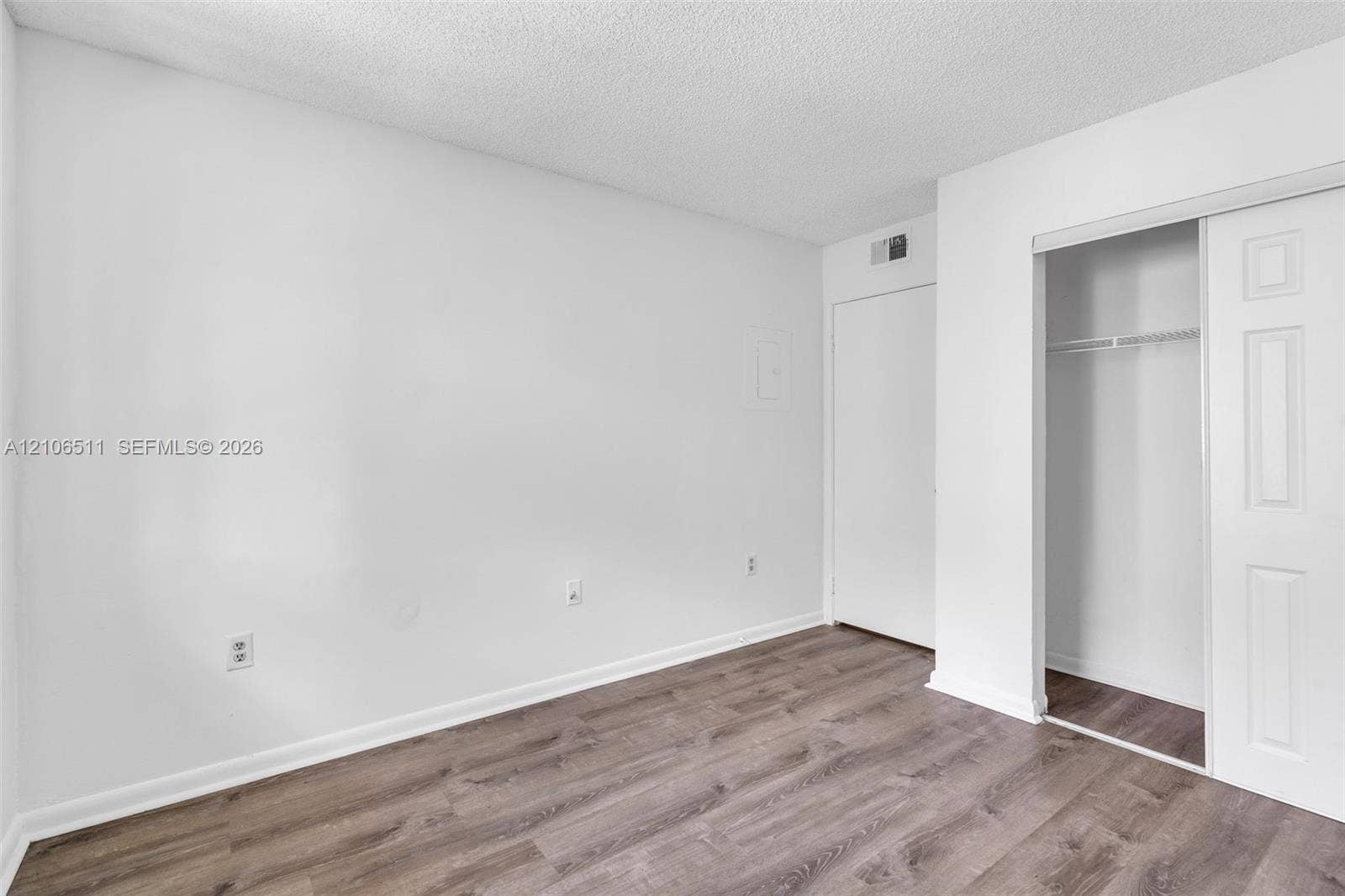 3229 Coral Lake Drive, #3229, Coral Springs, FL 33065 Room with wood-finish flooring, white walls, and a closet with sliding paneled doors