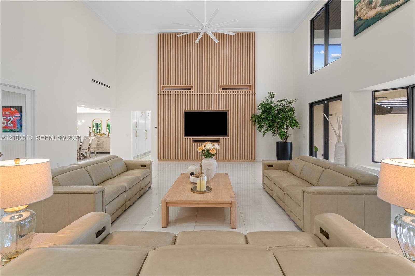 5720 SW 128th Street, Pinecrest, FL 33156 Double-height ceiling, wood-slat accent wall, large-format tile flooring, oversized windows, and multi-blade ceiling fan