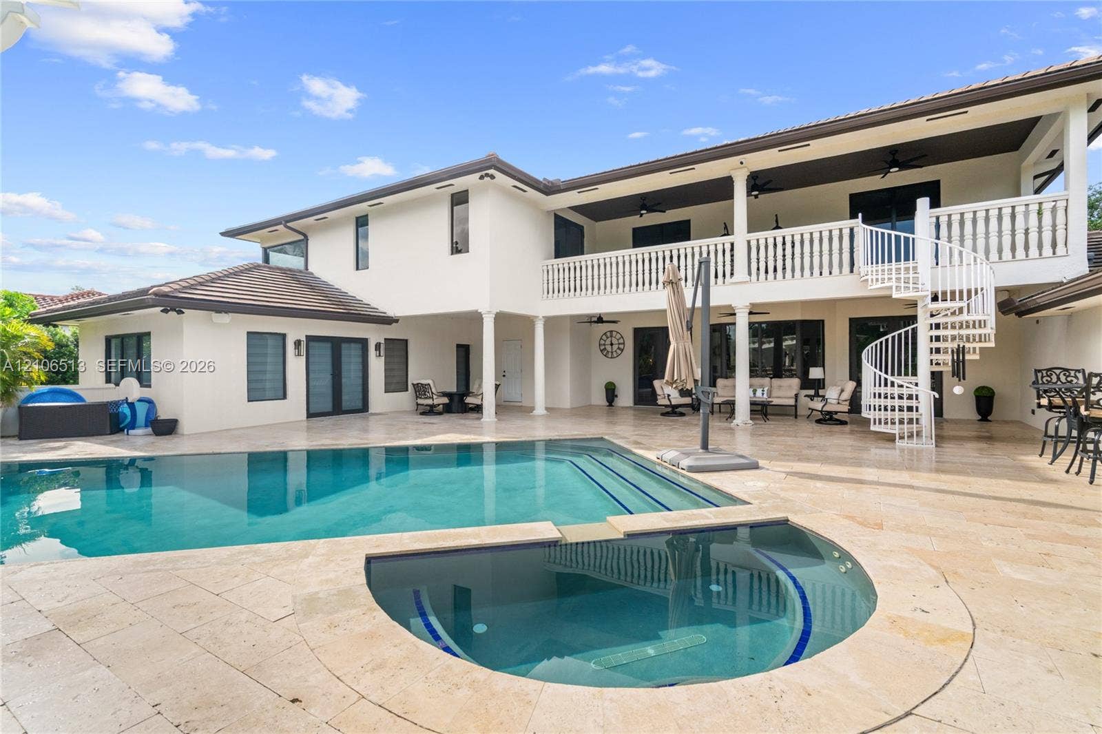 5720 SW 128th Street, Pinecrest, FL 33156 Stucco exterior featuring a dual-level covered patio, stone-finish pool deck, in-ground swimming pool with attached spa, and a white spiral staircase