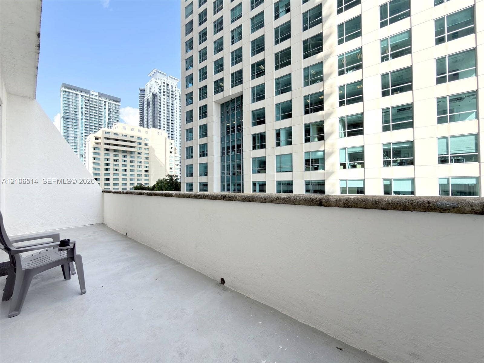 Private balcony featuring concrete flooring and a stone-topped masonry railing