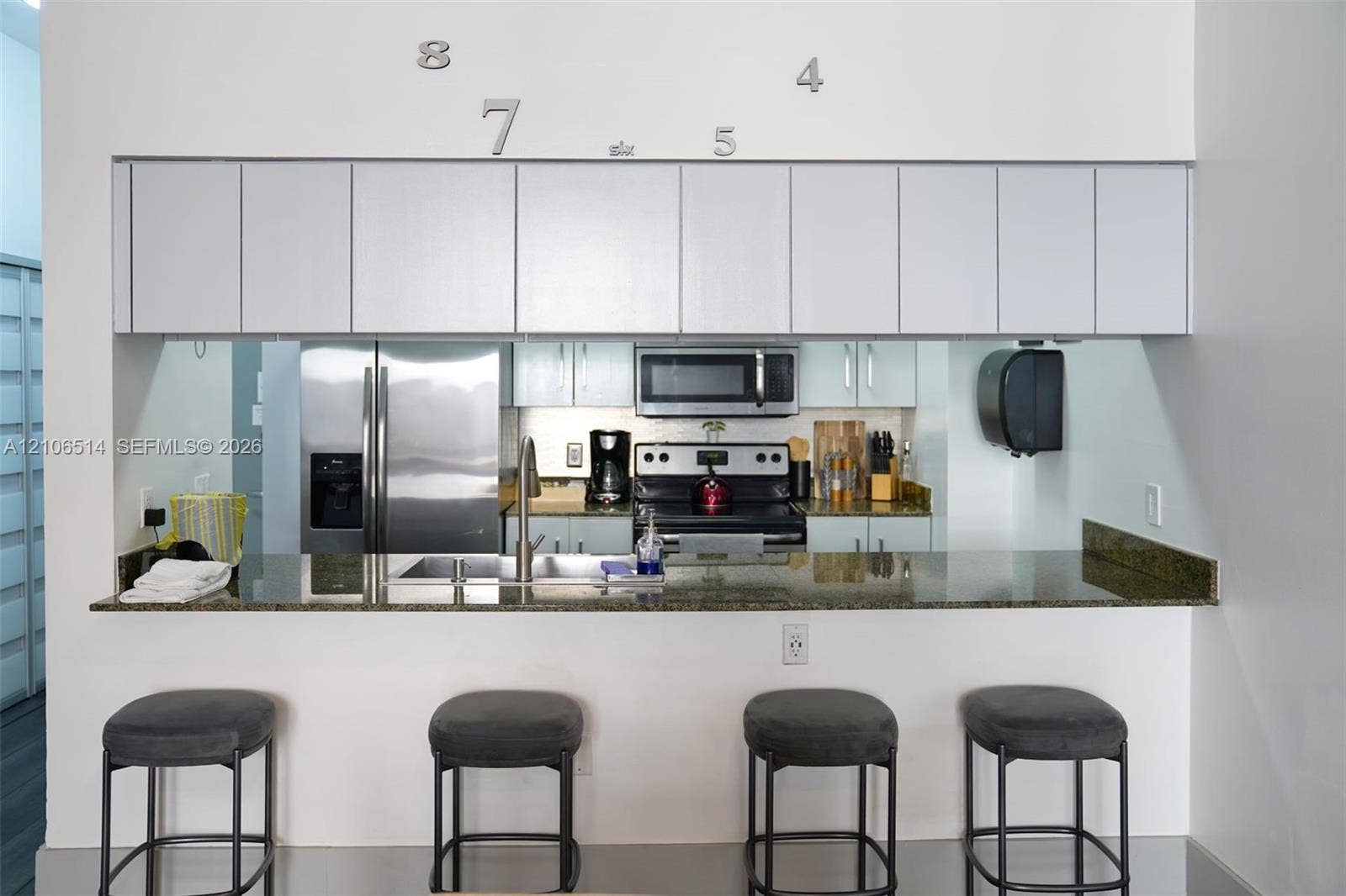 Kitchen featuring stone-finish countertops, stainless steel appliances, and wall-mounted cabinetry