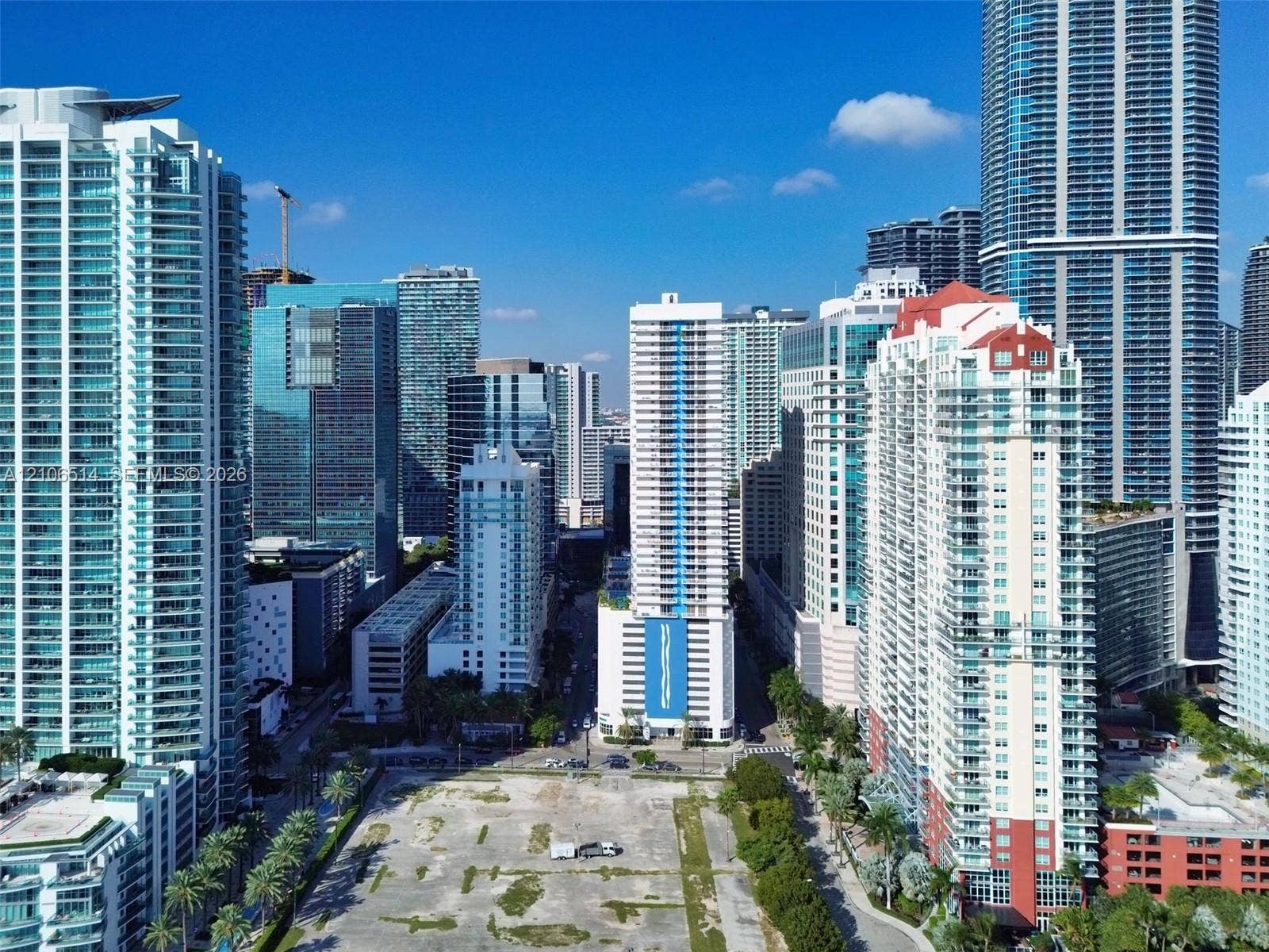 Aerial perspective featuring high-density urban infrastructure, surrounding glass-facade skyscrapers, and a central cleared parcel