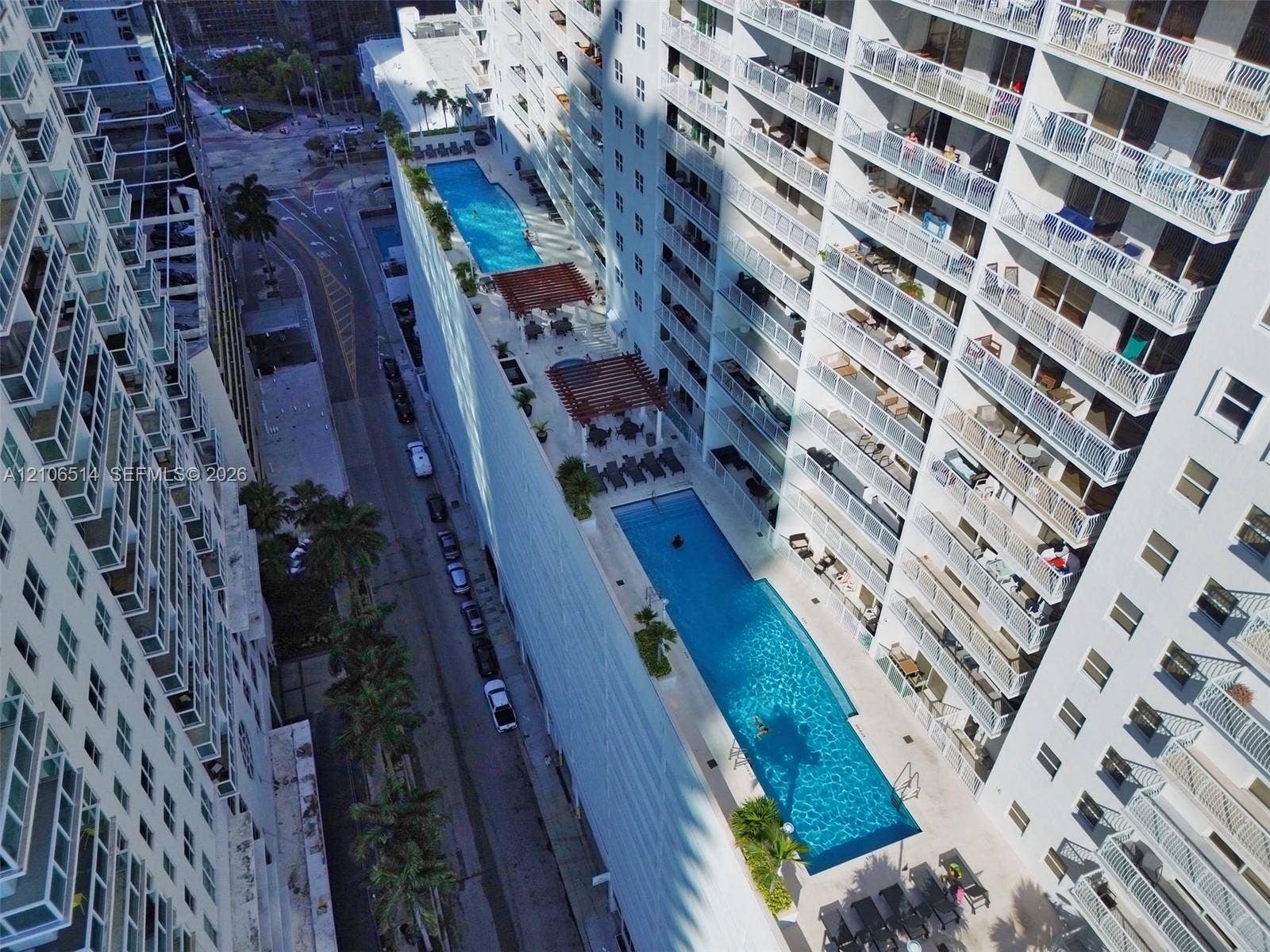 Elevated outdoor terrace featuring multiple swimming pools, paved sun decks, and shaded pergola structures