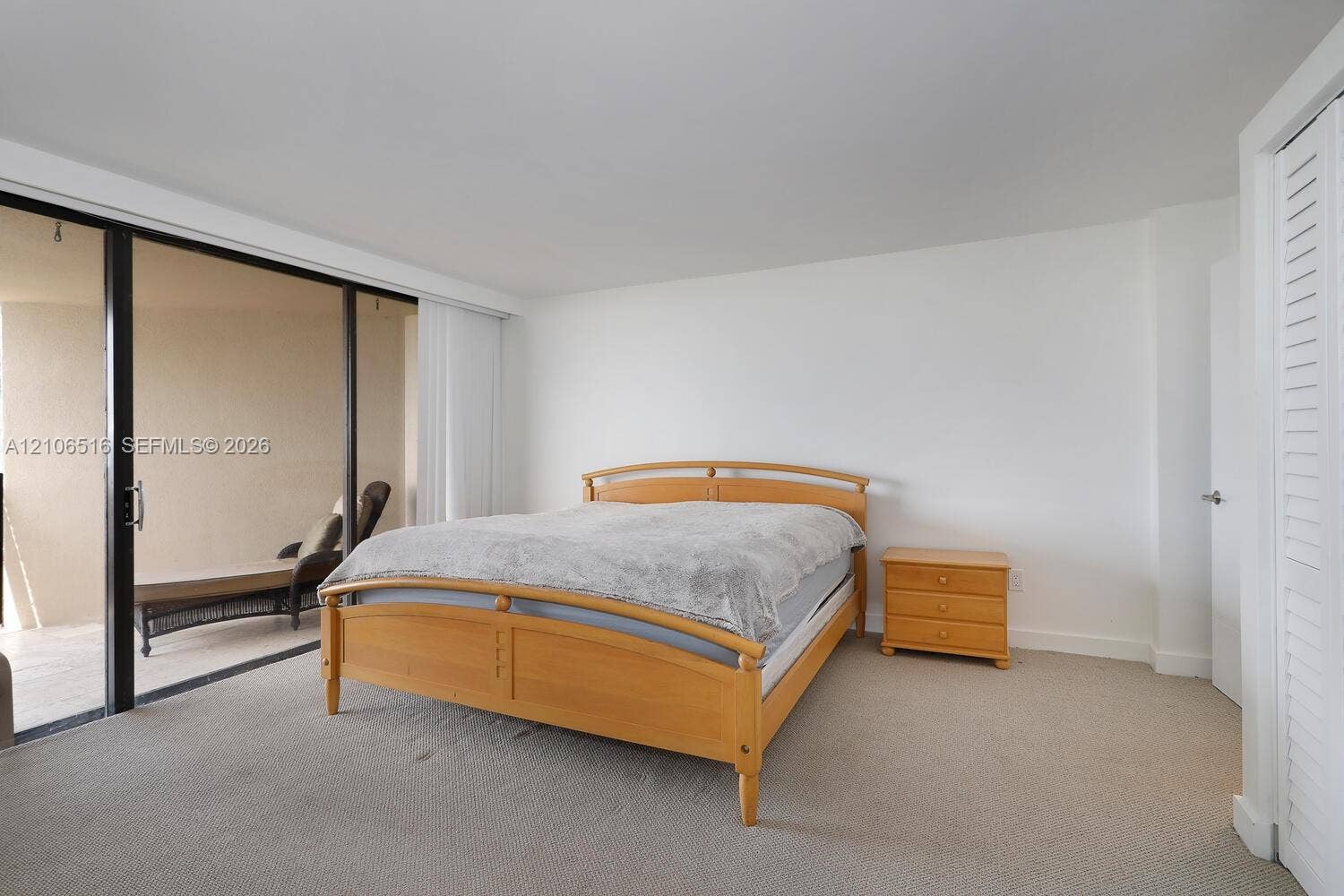 Neutral-toned carpeted flooring, floor-to-ceiling sliding glass doors, and louvered closet doors