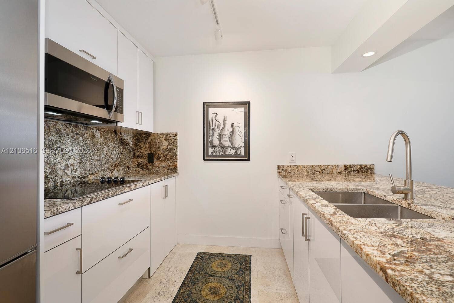 Kitchen featuring white flat-panel cabinetry, stone countertops, stainless steel appliances, and a dual-basin undermount sink with a gooseneck faucet