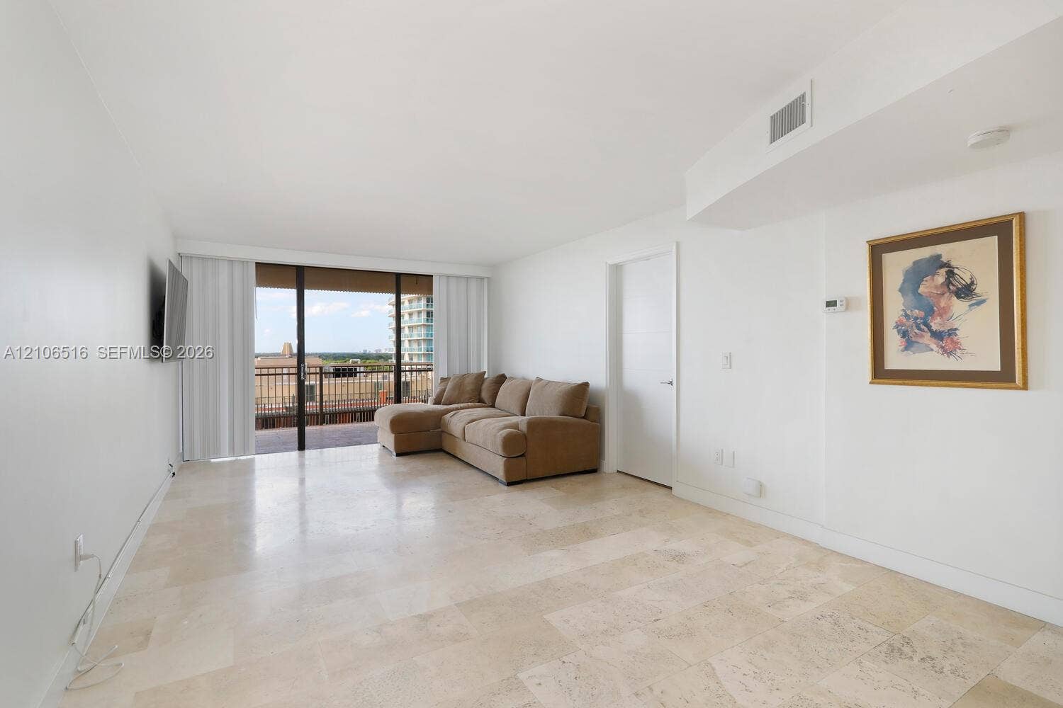 Open living area featuring large-format stone flooring, floor-to-ceiling sliding glass doors, and a private balcony