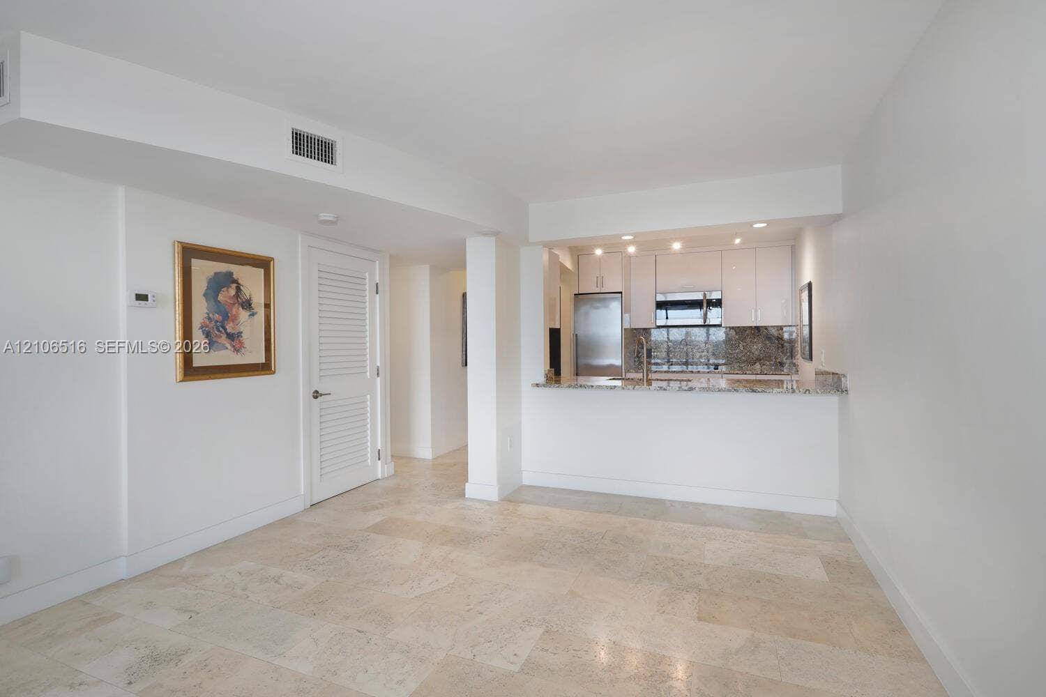 Stone tile flooring, white cabinetry, stone-finish countertops, stainless steel appliances, and recessed lighting