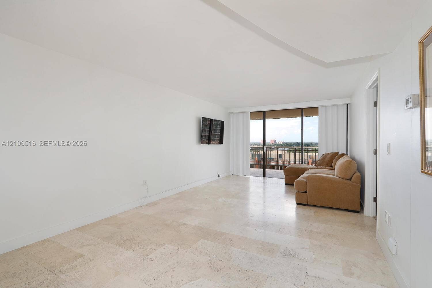 Living area featuring stone tile flooring, neutral wall finishes, and floor-to-ceiling sliding glass doors opening to an exterior balcony