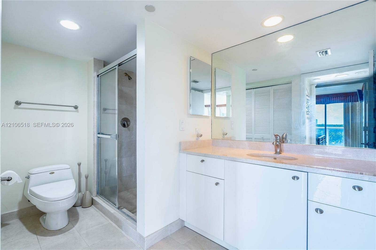 16500 Collins Avenue, #554, Sunny Isles Beach, FL 33160 Bathroom featuring white cabinetry, solid-surface countertop, full-width wall mirror, glass-enclosed shower, and recessed lighting