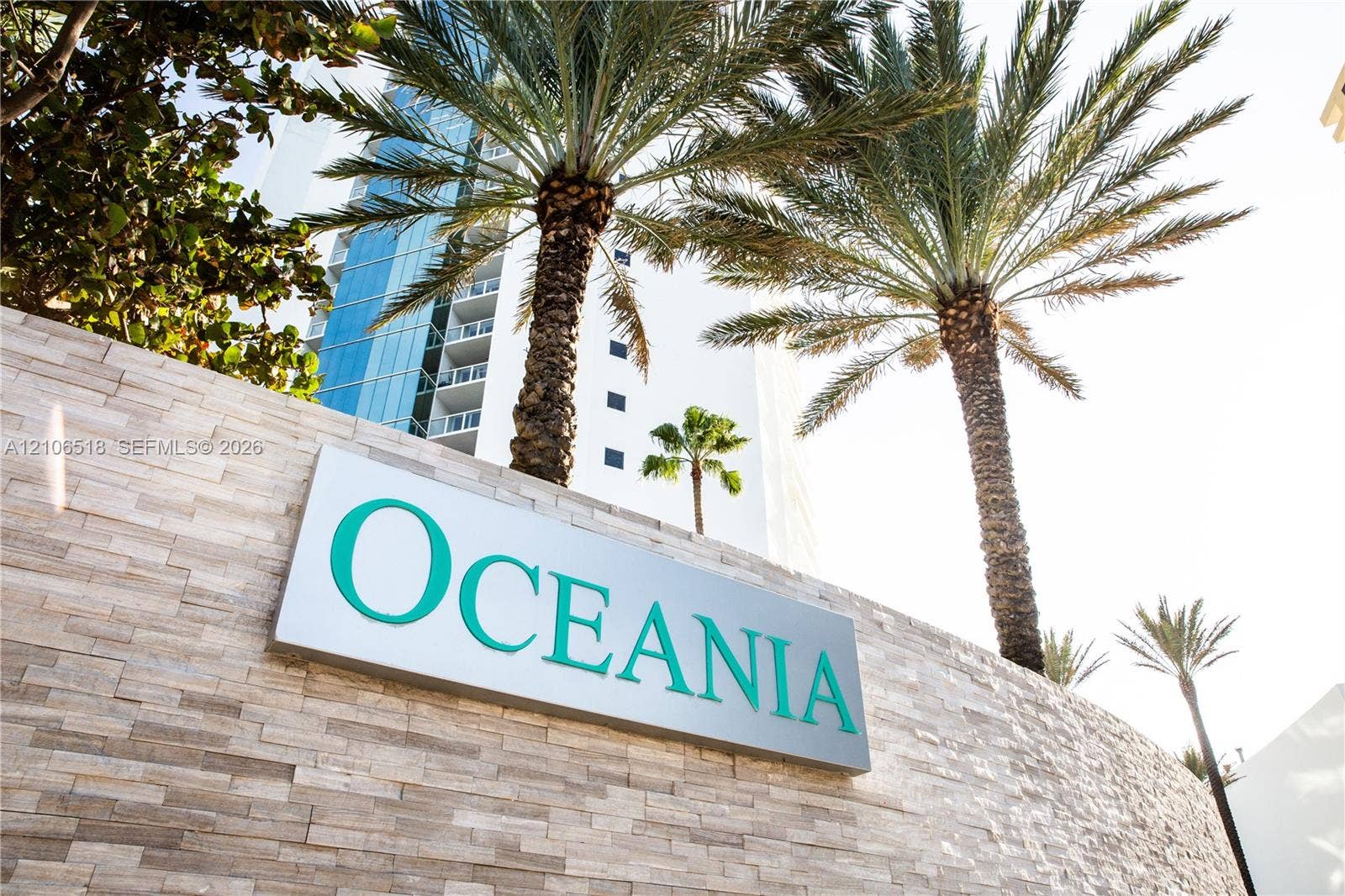 16500 Collins Avenue, #554, Sunny Isles Beach, FL 33160 Textured stone masonry wall featuring high-rise building architecture and mature palm trees
