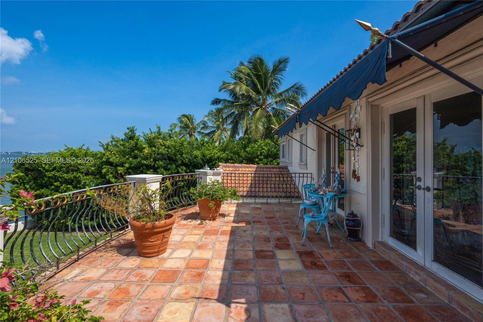 4760 N Bay Road, Miami Beach, FL 33140 Terrace featuring terracotta tile flooring, wrought-iron railings, a retractable fabric awning, and dual-pane glass doors