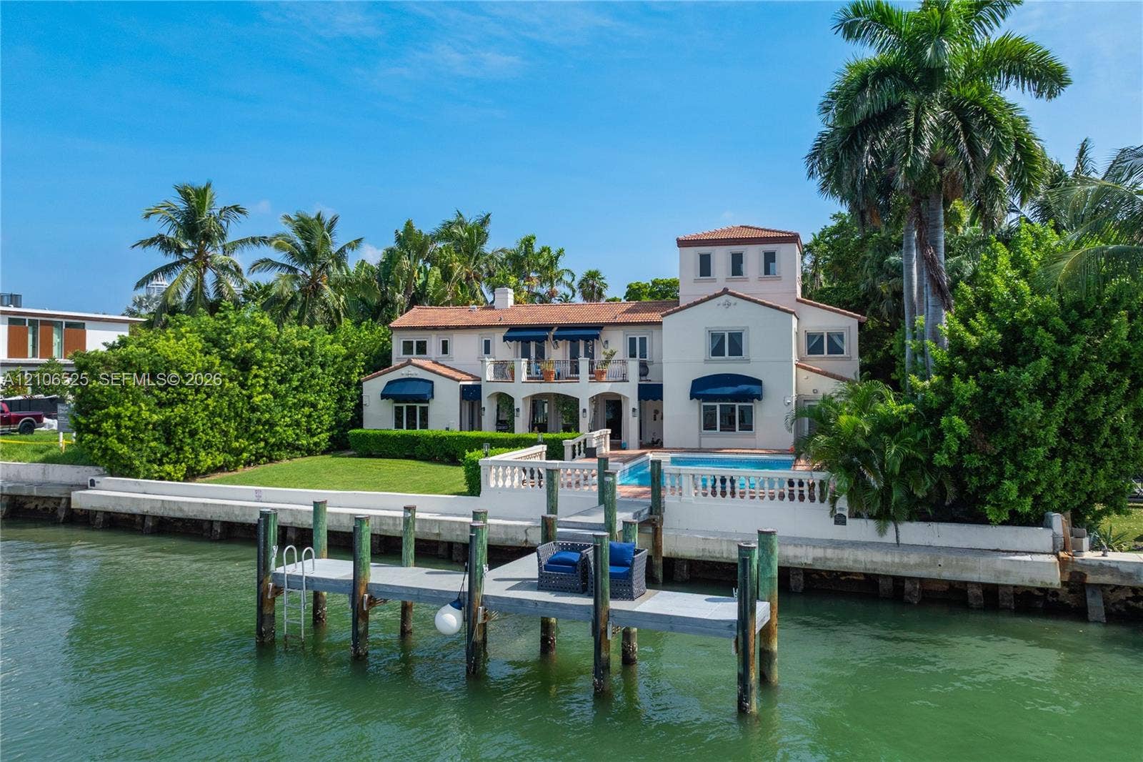 4760 N Bay Road, Miami Beach, FL 33140 Waterfront residence featuring a private dock, swimming pool, second-story balcony, and terracotta-style roof tiles