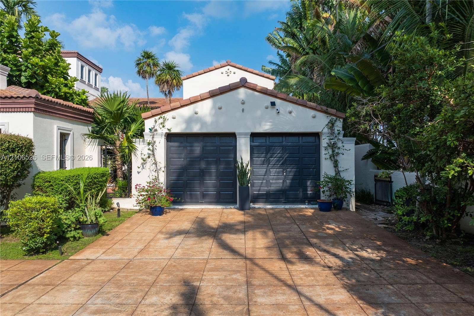4760 N Bay Road, Miami Beach, FL 33140 Detached two-car garage with charcoal-finished sectional doors, stucco exterior, tile roofing, and a paved driveway