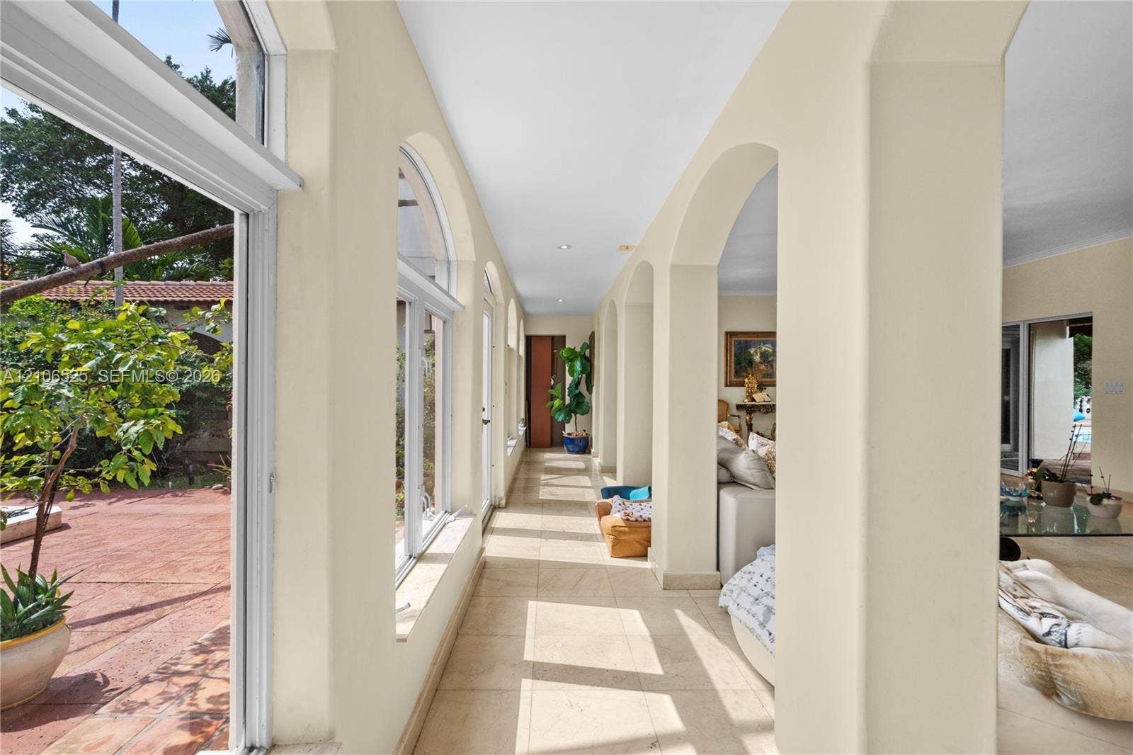 4760 N Bay Road, Miami Beach, FL 33140 Hallway featuring an arched colonnade, tile flooring, and floor-to-ceiling windows