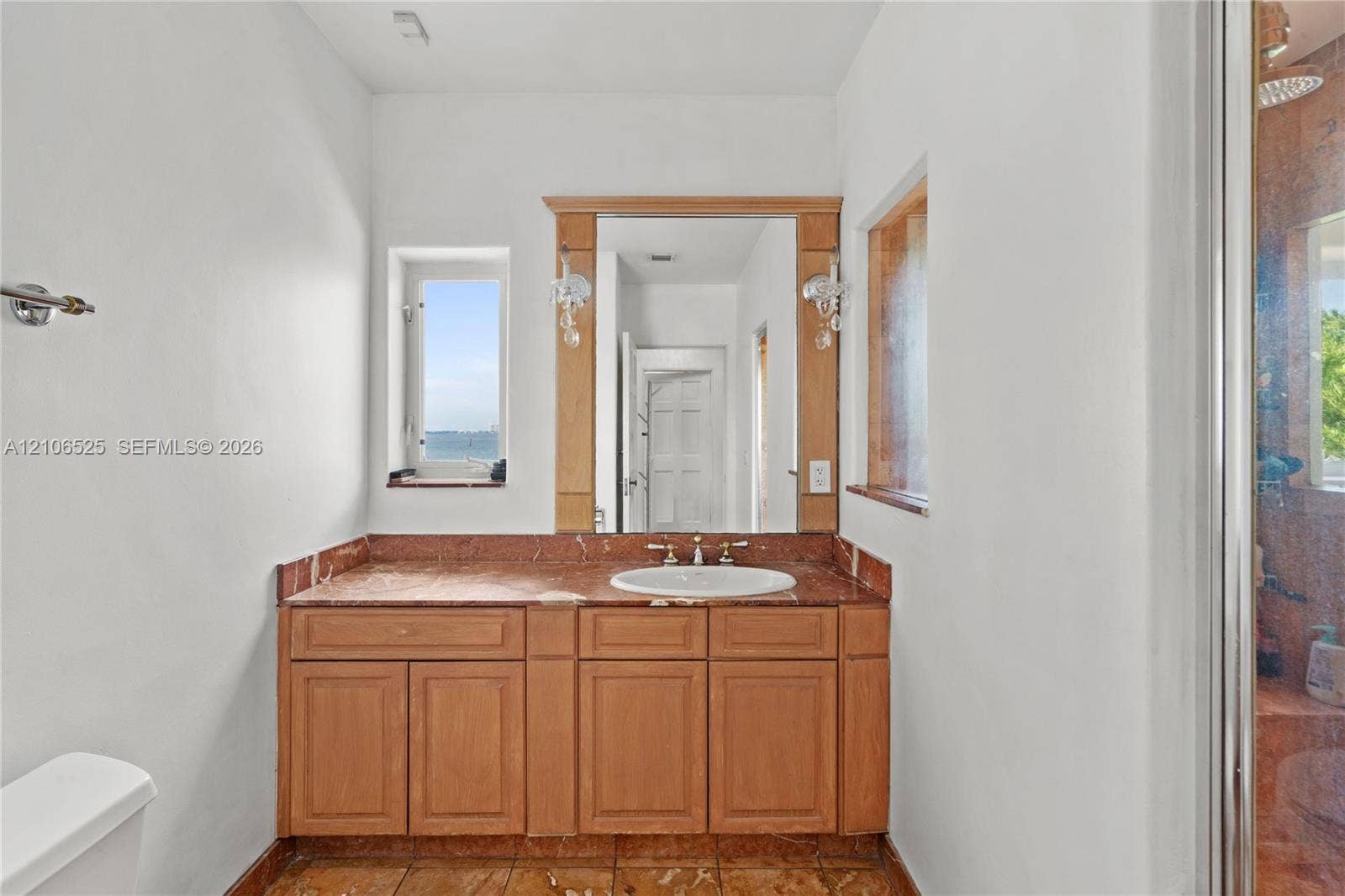 4760 N Bay Road, Miami Beach, FL 33140 Bathroom featuring a stone-topped vanity with wood cabinetry, an integrated sink, dual wall-mounted light fixtures, and stone flooring