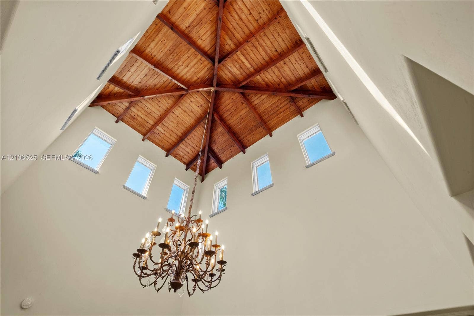 4760 N Bay Road, Miami Beach, FL 33140 Vaulted ceiling with exposed wood-plank beams, clerestory windows, and a multi-tiered metal chandelier