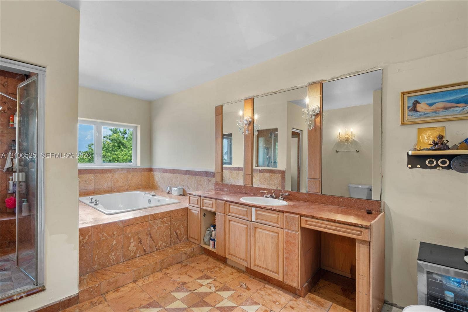 4760 N Bay Road, Miami Beach, FL 33140 Bathroom featuring a stone-clad jetted soaking tub, custom wood cabinetry with a stone countertop, a recessed vanity area, integrated wall-to-wall mirrors, and stone tile flooring