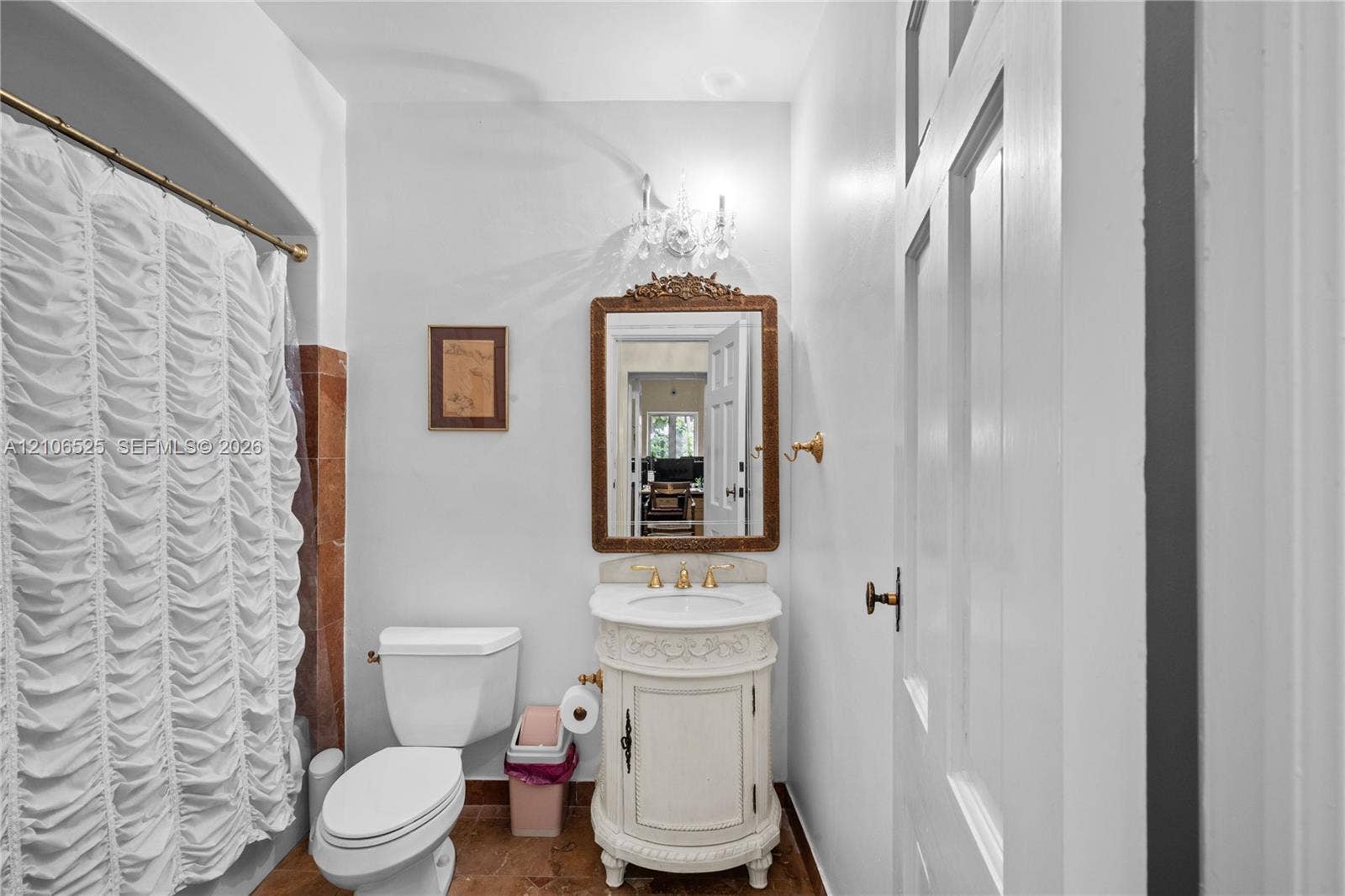 4760 N Bay Road, Miami Beach, FL 33140 Decorative vanity with carved detailing, stone countertop, gold-toned faucet, wall-mounted light fixture, and framed wall mirror