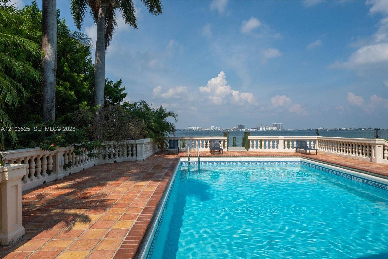 4760 N Bay Road, Miami Beach, FL 33140 Swimming pool with tile surround, terracotta paver decking, decorative stone balustrade, and direct waterfront access