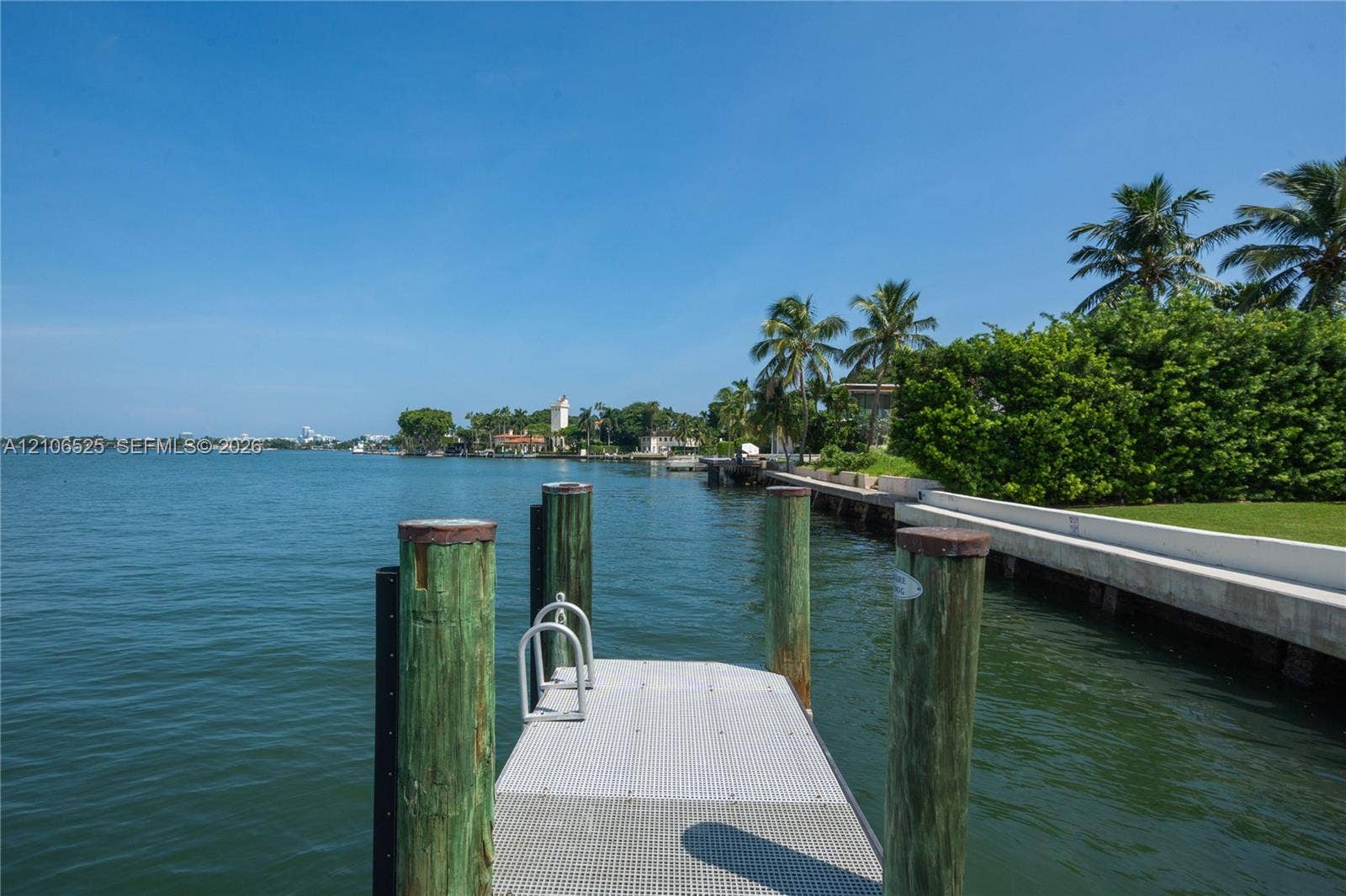 4760 N Bay Road, Miami Beach, FL 33140 Private waterfront dock with industrial-grade metal decking, timber pilings, and integrated swim ladder, featuring expansive open-water frontage and a concrete seawall