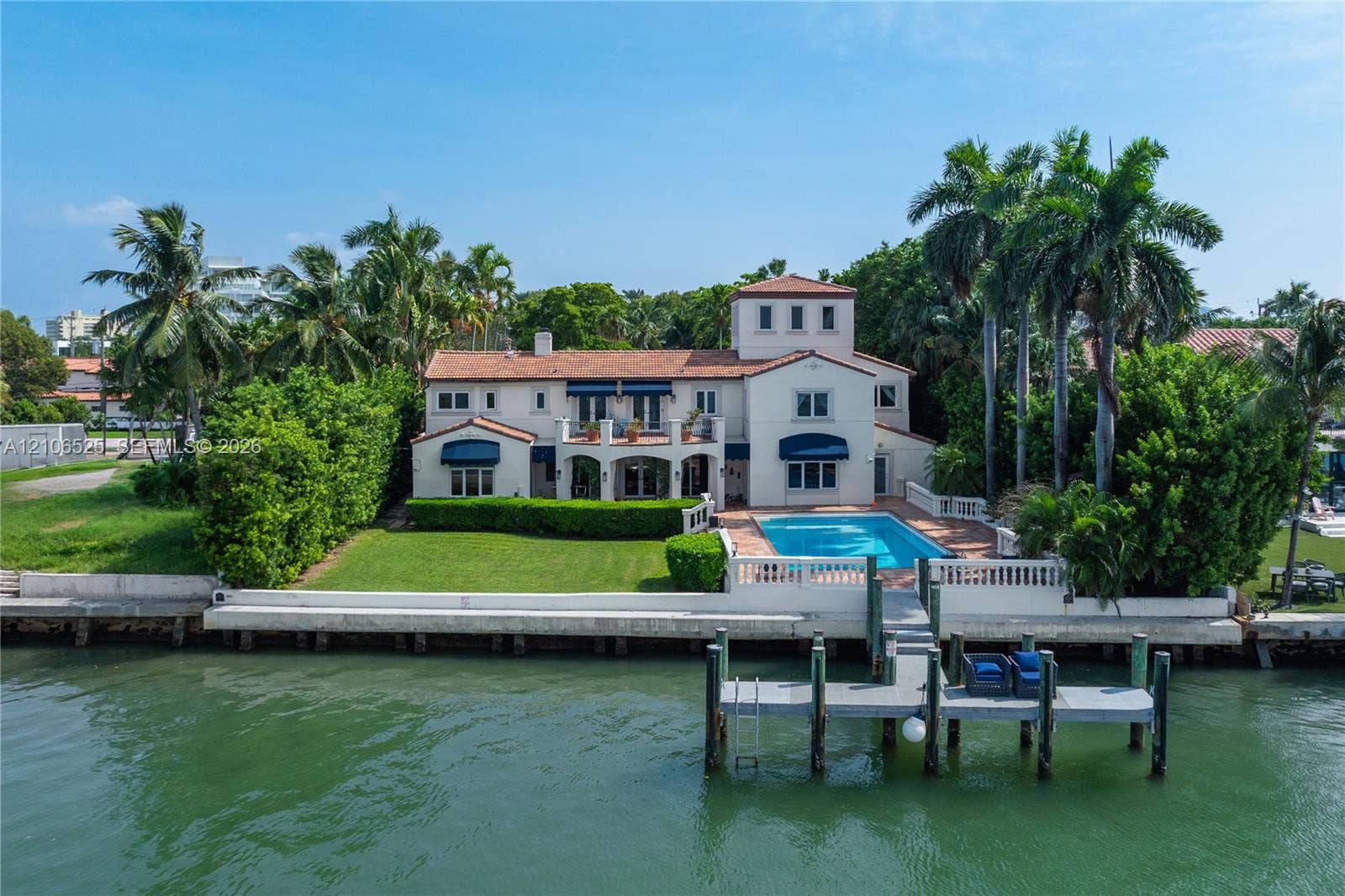 4760 N Bay Road, Miami Beach, FL 33140 Waterfront residence featuring a private dock, swimming pool, tiled roof, and expansive lawn