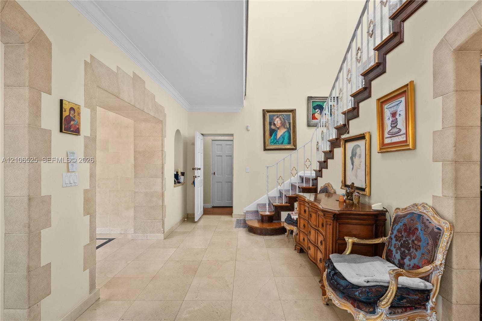 4760 N Bay Road, Miami Beach, FL 33140 Foyer featuring high ceilings, stone-trimmed arched entryways, large-format tile flooring, and a staircase with ornate metal railings