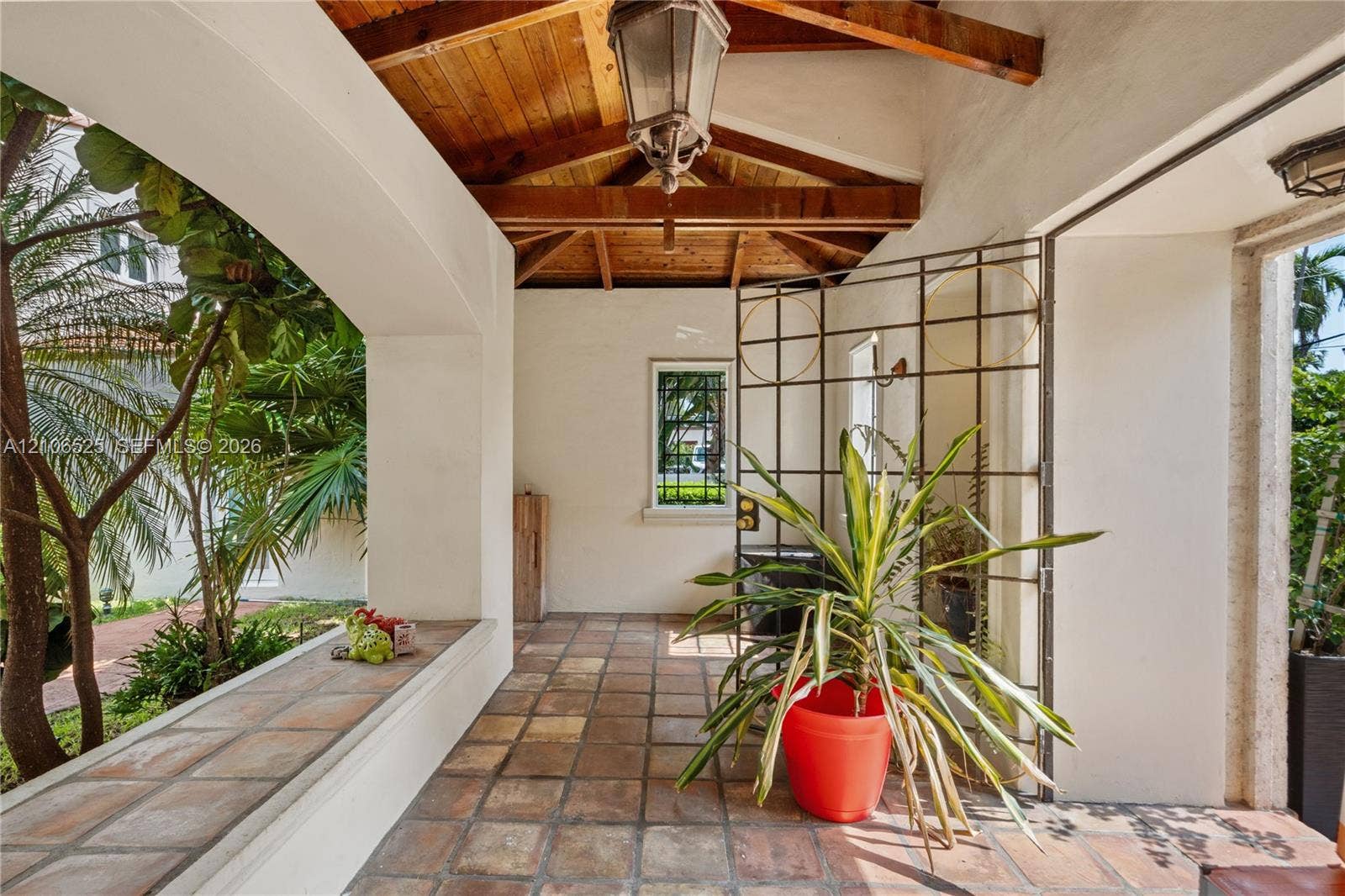 4760 N Bay Road, Miami Beach, FL 33140 Covered patio featuring an exposed wood-beam ceiling, tile flooring, built-in bench seating, and an ornamental metal gate