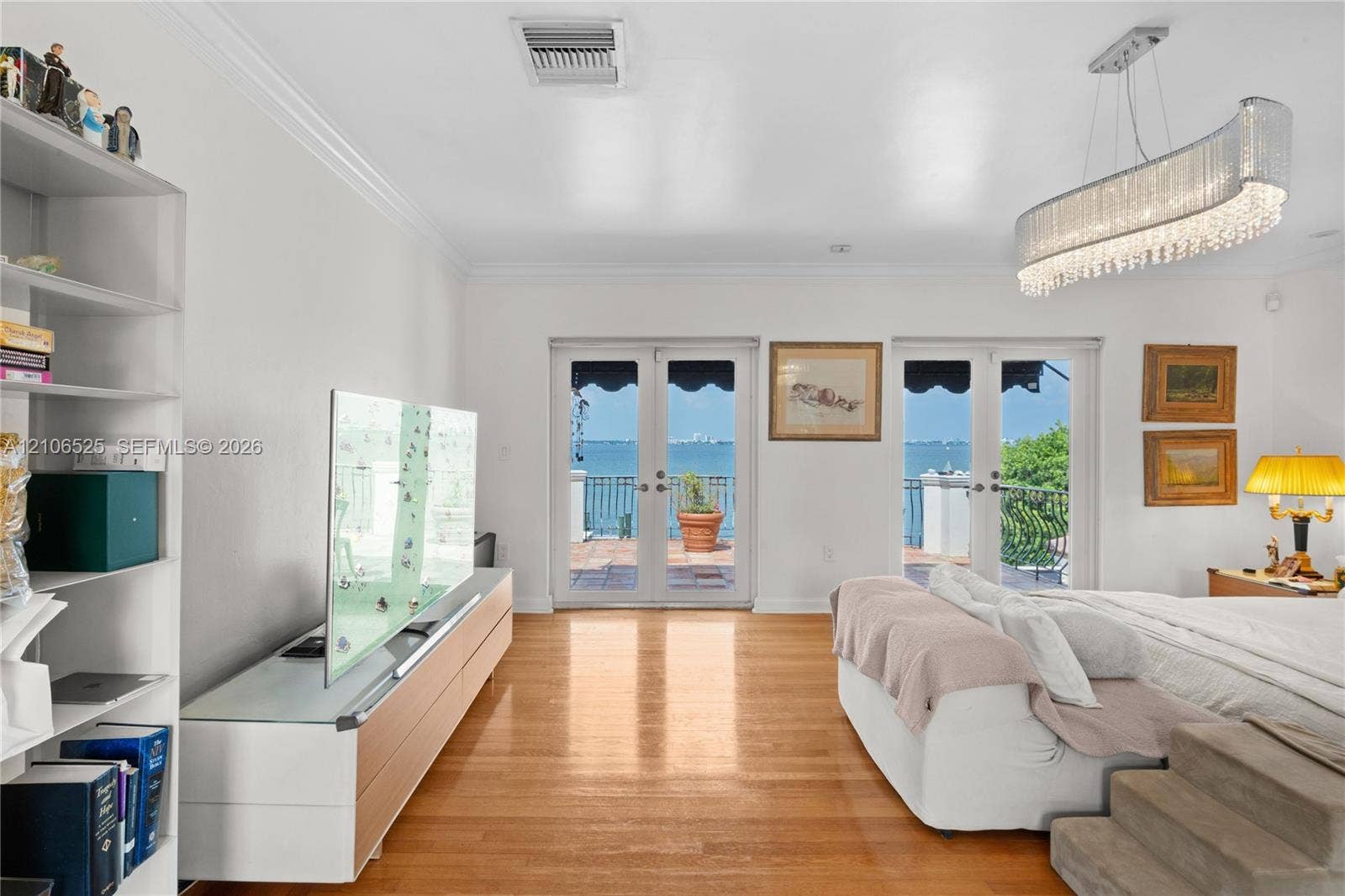 4760 N Bay Road, Miami Beach, FL 33140 Wood-finish flooring, dual French doors, crystal-accented chandelier, and water backdrop