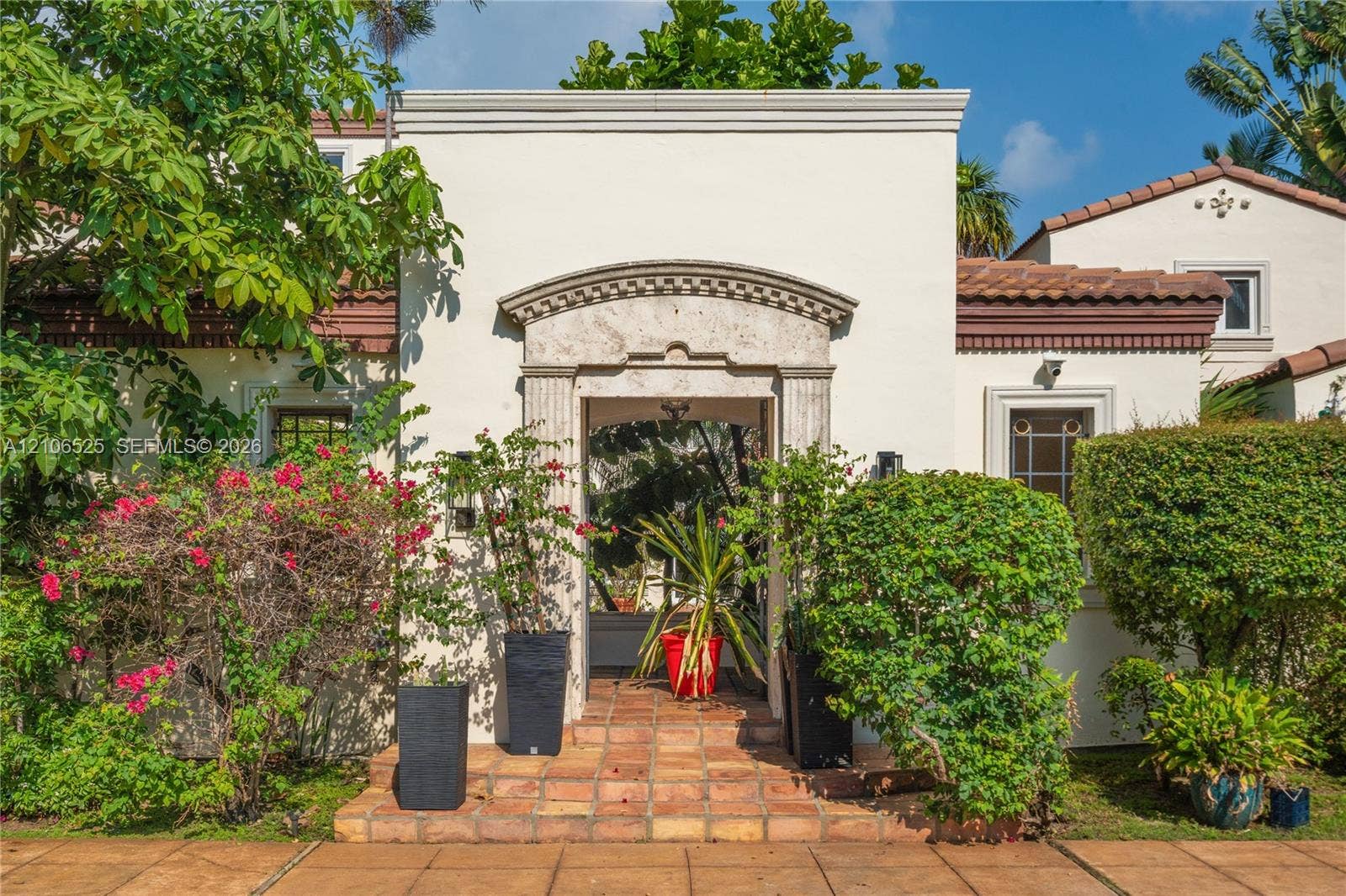 4760 N Bay Road, Miami Beach, FL 33140 Stucco exterior featuring a decorative stone entryway arch, terra-cotta tile flooring, and terracotta roof accents