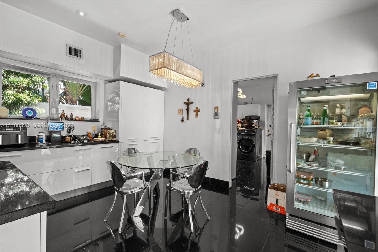 4760 N Bay Road, Miami Beach, FL 33140 Glossy cabinetry featuring integrated storage, black stone countertops, high-gloss tile flooring, and a rectangular crystal-accented pendant light fixture