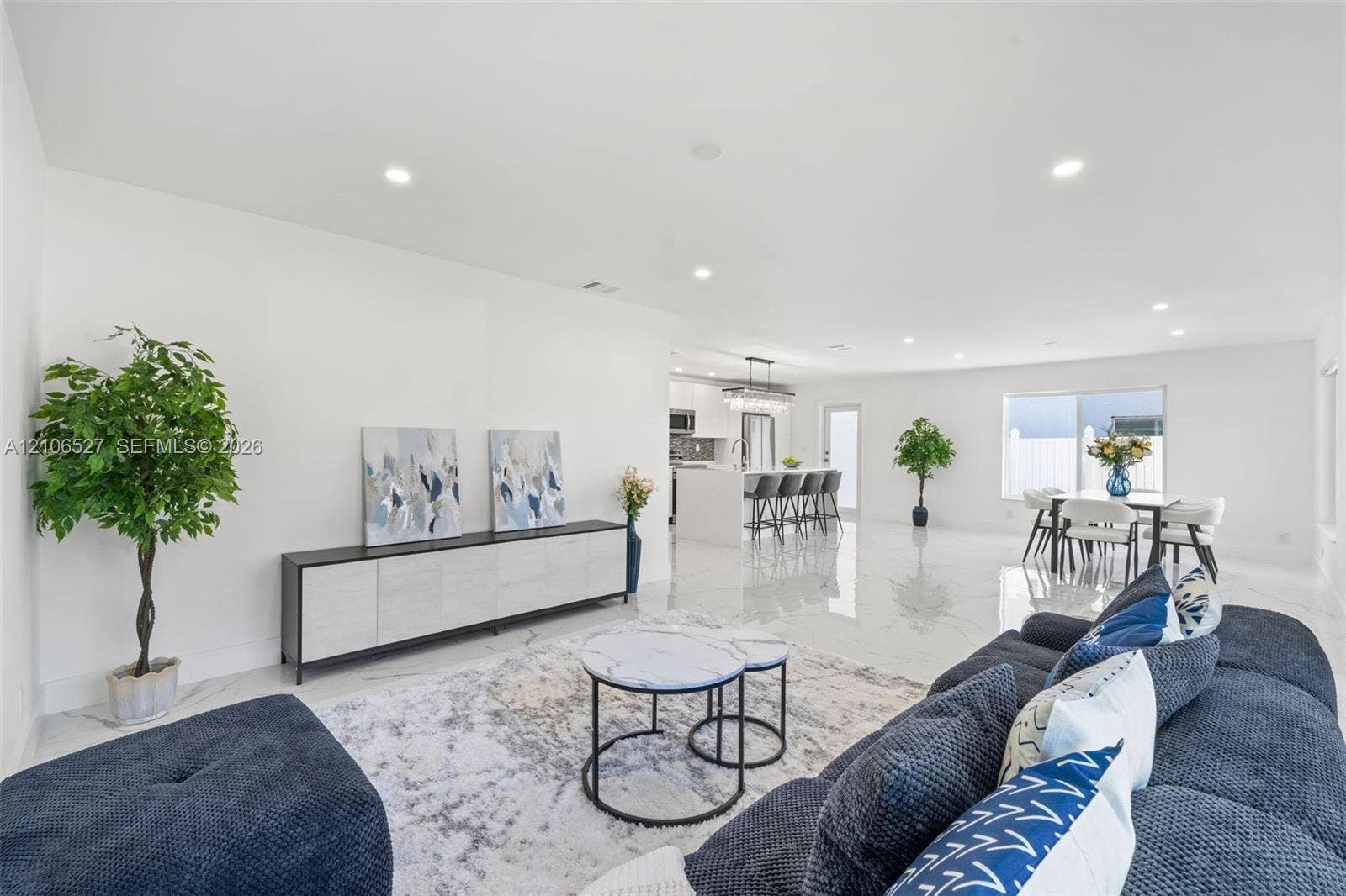 Open-concept interior featuring large-format tile flooring, recessed lighting, and a kitchen island with stone-finish countertops