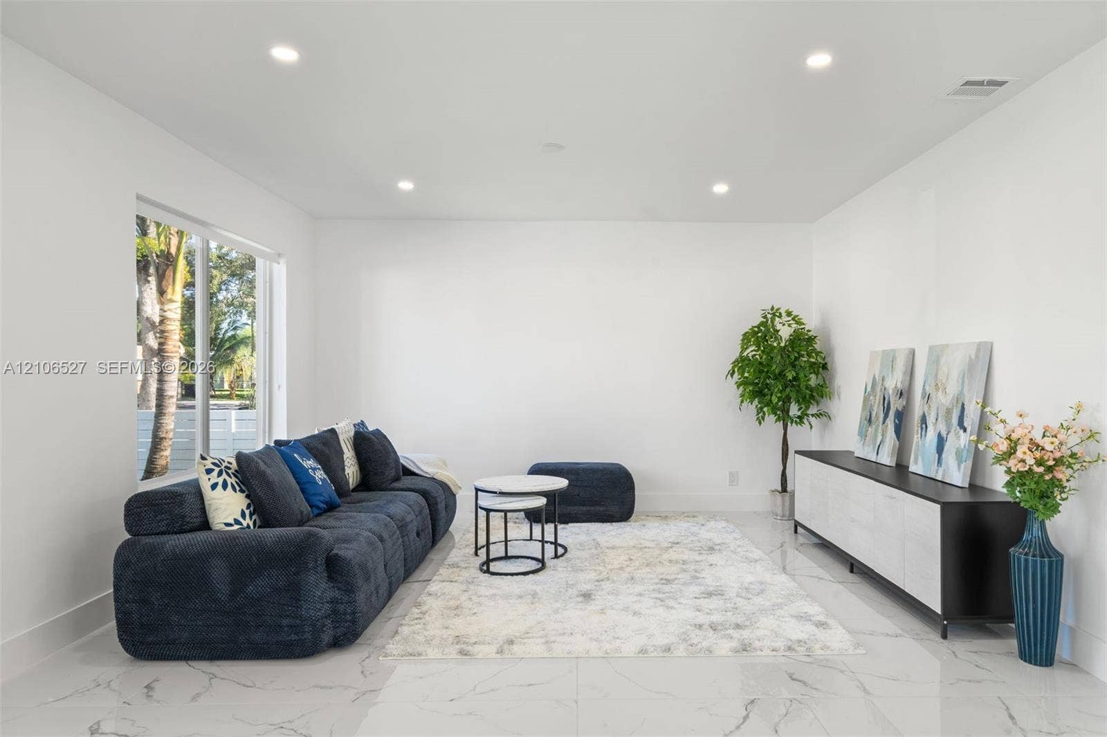 Neutral-toned interior featuring large-format tile flooring, recessed lighting, and a wide sliding glass door
