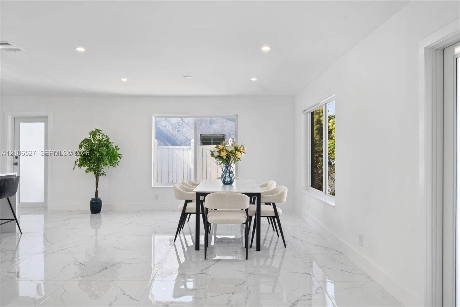 Open-concept interior featuring large-format polished stone-finish floor tiles, recessed ceiling lighting, and multiple windows