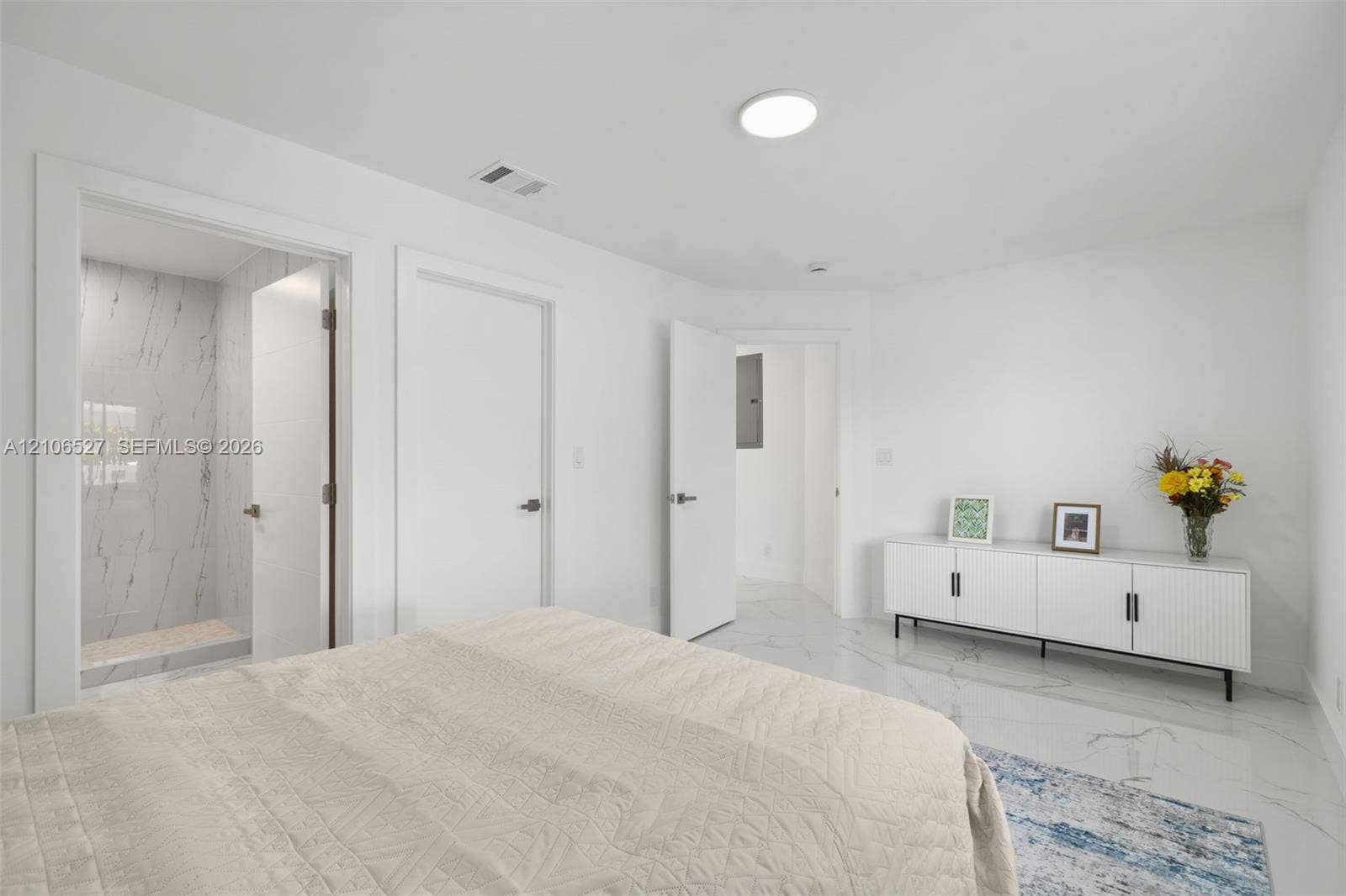 Room featuring white-finish tile flooring with gray veining, flush-mount lighting, and an enclosed shower stall with floor-to-ceiling veined tile wall surfacing