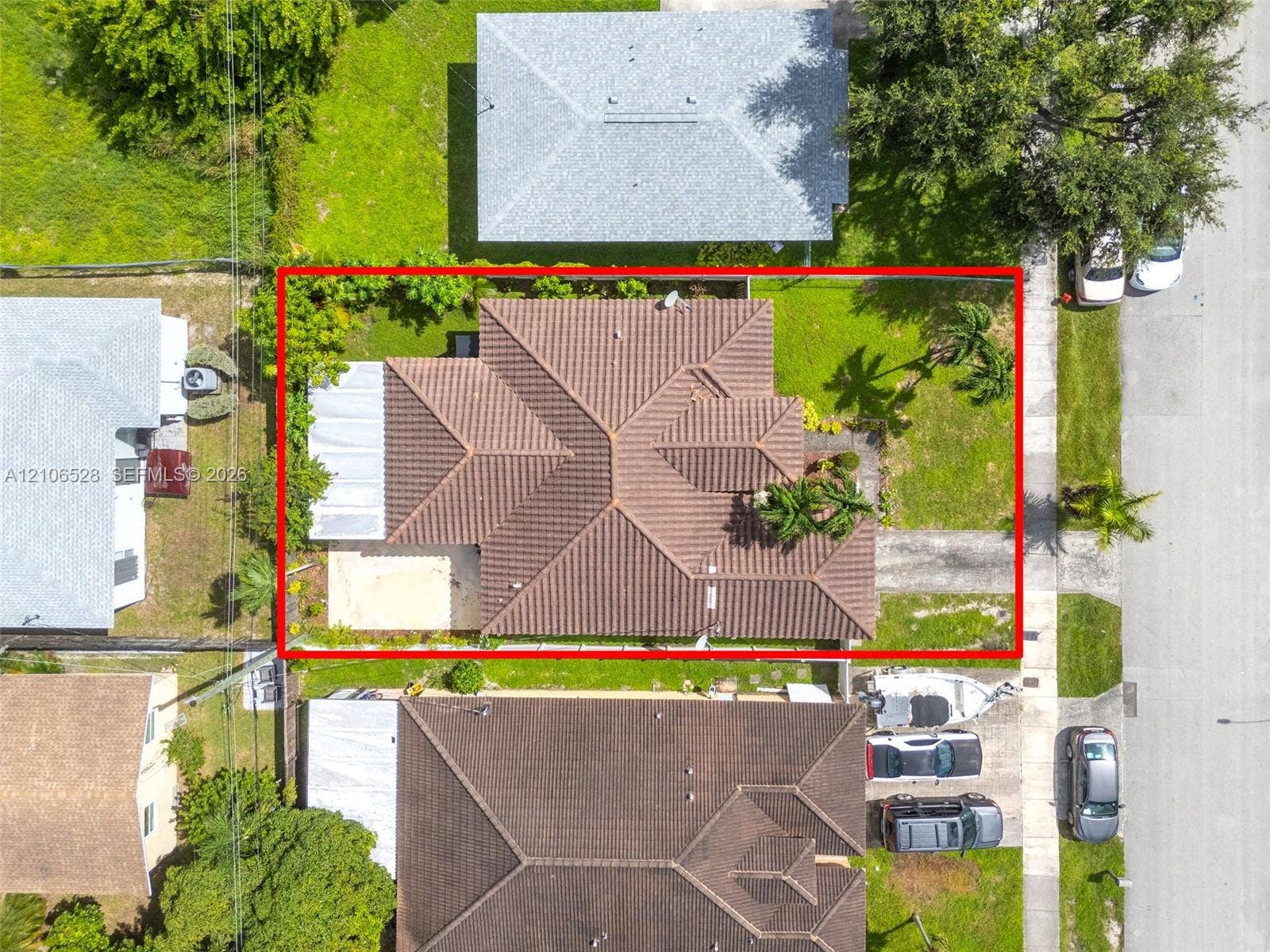 2615 NW 14th Street, Fort Lauderdale, FL 33311 Aerial perspective of a property featuring a tile roof, paved driveway, concrete patio, and fenced grounds with mature landscaping