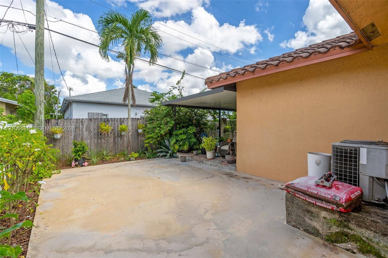 2615 NW 14th Street, Fort Lauderdale, FL 33311 Exterior space featuring a covered patio, concrete hardscaping, wood-style fencing, and established tropical landscaping