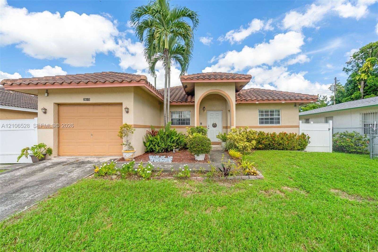 2615 NW 14th Street, Fort Lauderdale, FL 33311 Stucco exterior featuring a tiled roof, arched entryway, single-car garage, and established landscaping