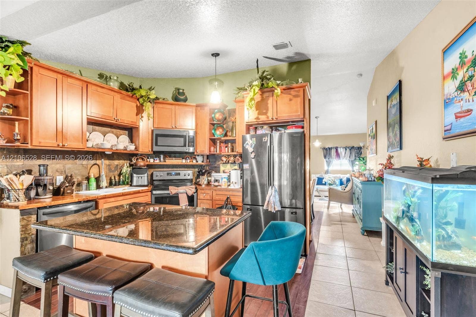 2615 NW 14th Street, Fort Lauderdale, FL 33311 Kitchen featuring wood cabinetry, a stone-surfaced island, a tiled backsplash, and stainless steel appliances