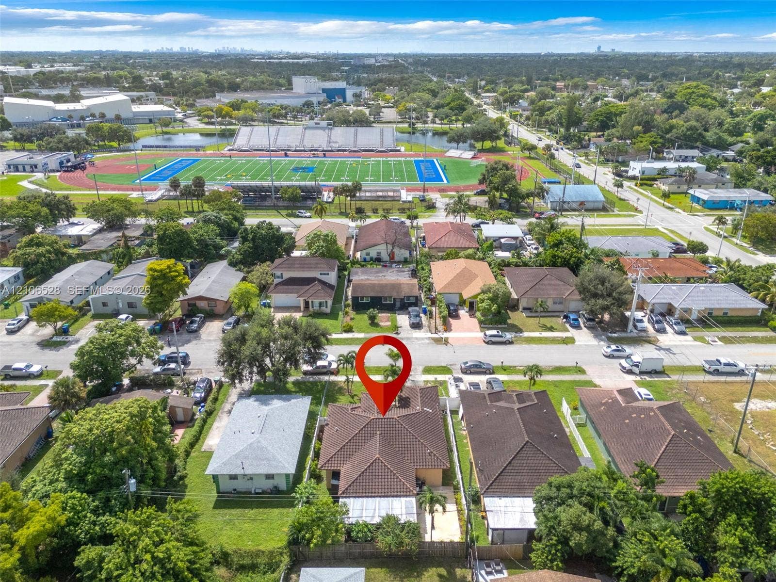 2615 NW 14th Street, Fort Lauderdale, FL 33311 Aerial perspective of a residential property featuring a hip-style roof, an expansive backyard, and established tree canopy, situated within a grid-patterned neighborhood with proximity to athletic facilities