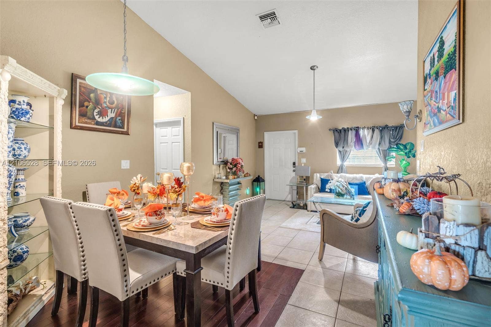 2615 NW 14th Street, Fort Lauderdale, FL 33311 Vaulted ceilings, built-in display shelving, neutral paint palette, pendant lighting, and mixed flooring featuring both ceramic tile and dark wood-finish surfaces
