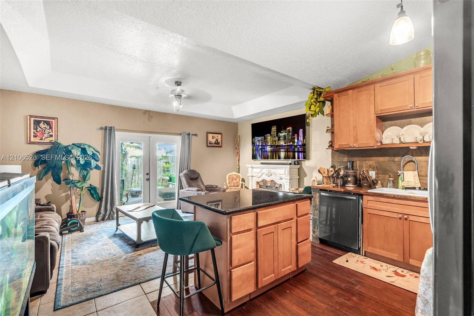2615 NW 14th Street, Fort Lauderdale, FL 33311 Kitchen featuring wood cabinetry, dark stone-topped island, tile backsplash, tray ceiling, and dual glass pane doors